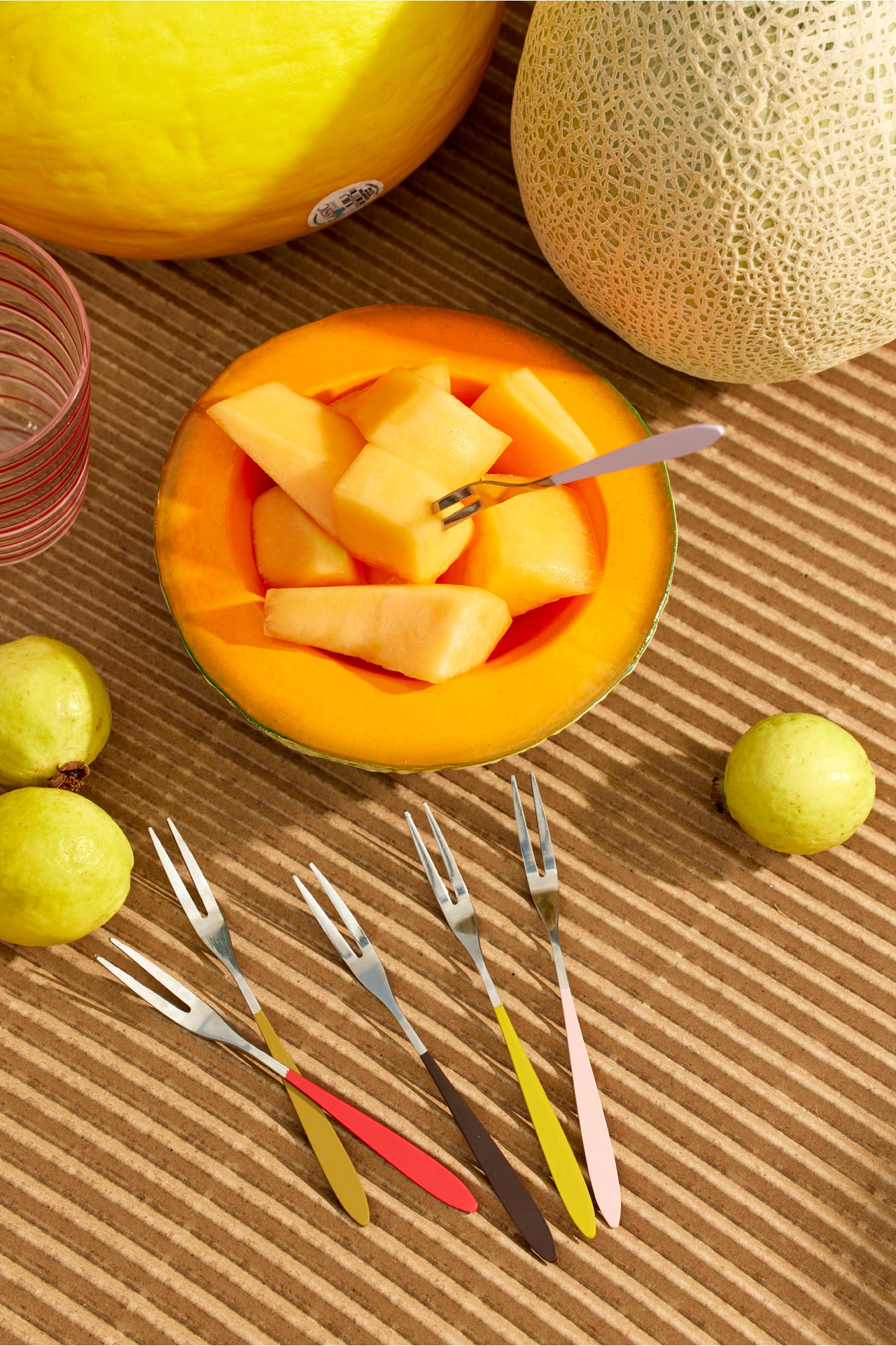 Aperitif forks with colorful handles in melon bowl.