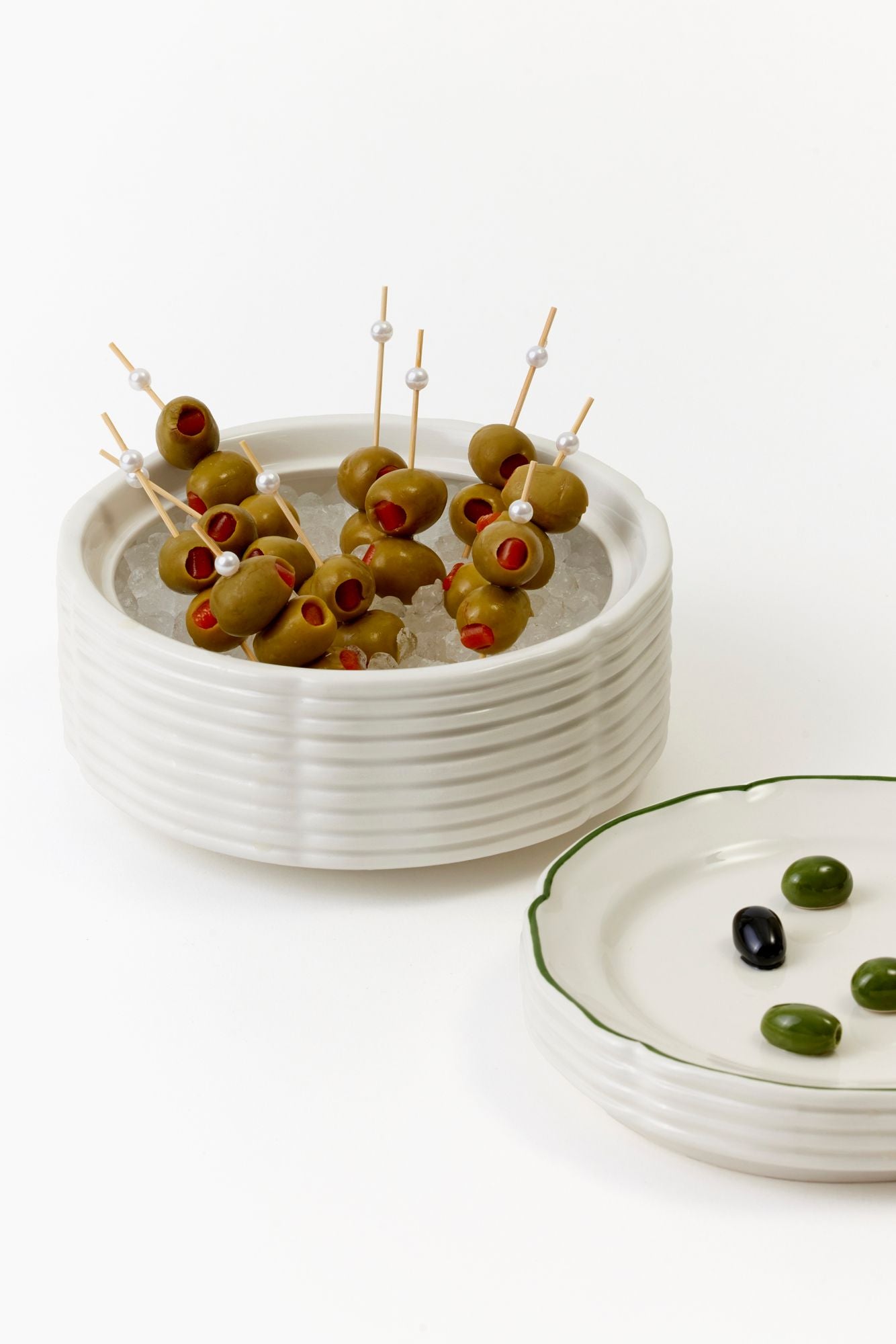 White ceramic bowl with skewered olives on a white background