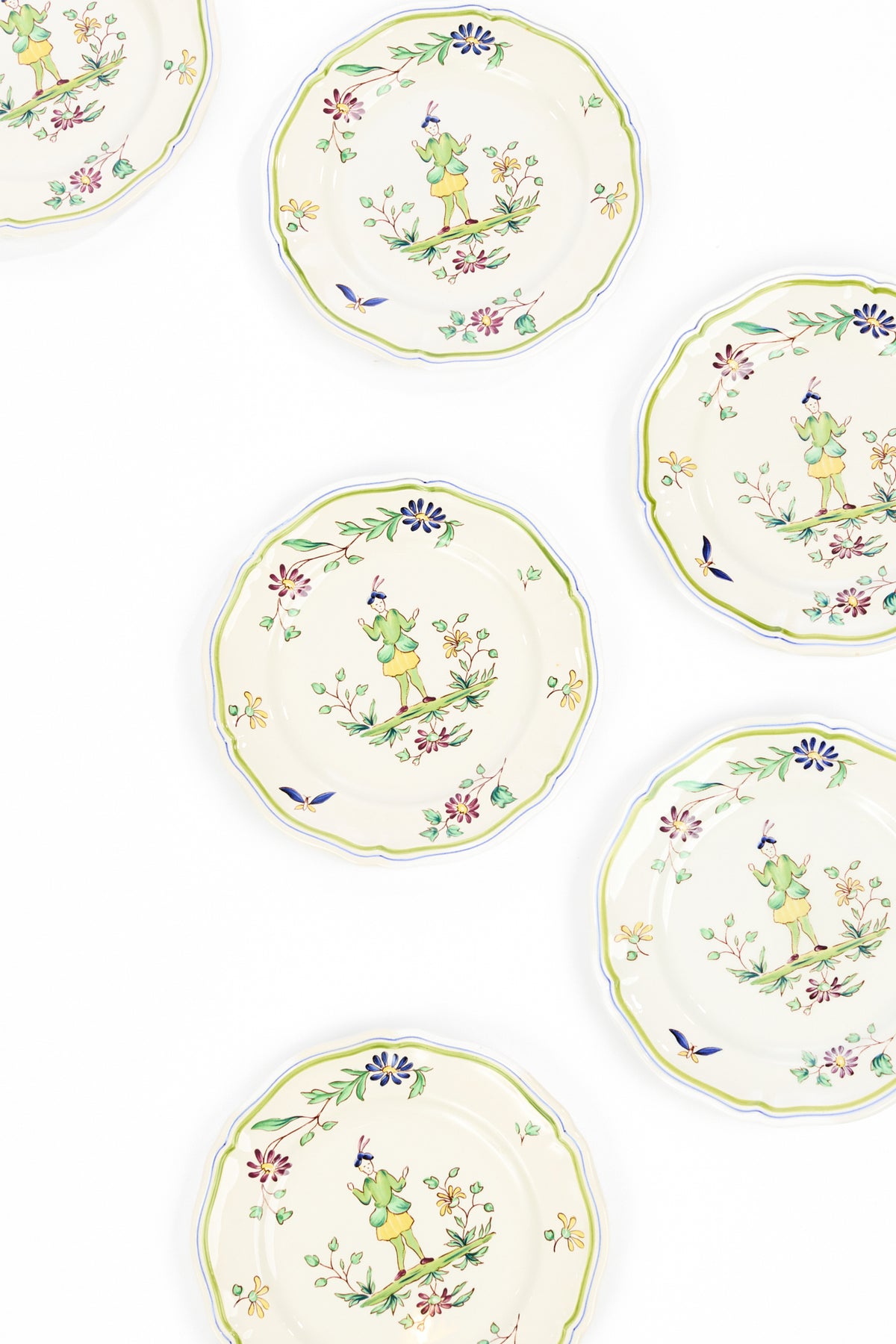 Six round ceramic plates with scalloped edges, featuring a vintage-style illustration of a person in a hat surrounded by flowers and leaves, arranged on a clean white background.