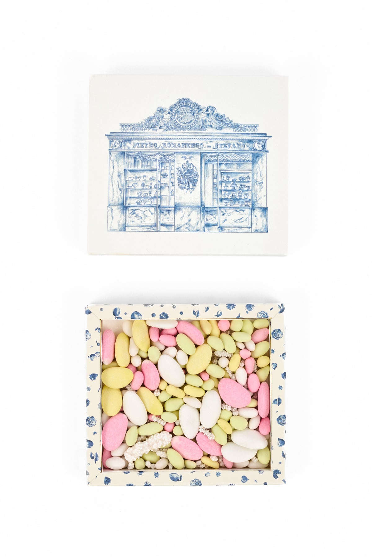 A boxed assortment of pastel-colored candy, shown with its lid above on a white background. The lid features a blue architectural illustration with the text 'PETER SCHARPMER - STRASBOURG'.