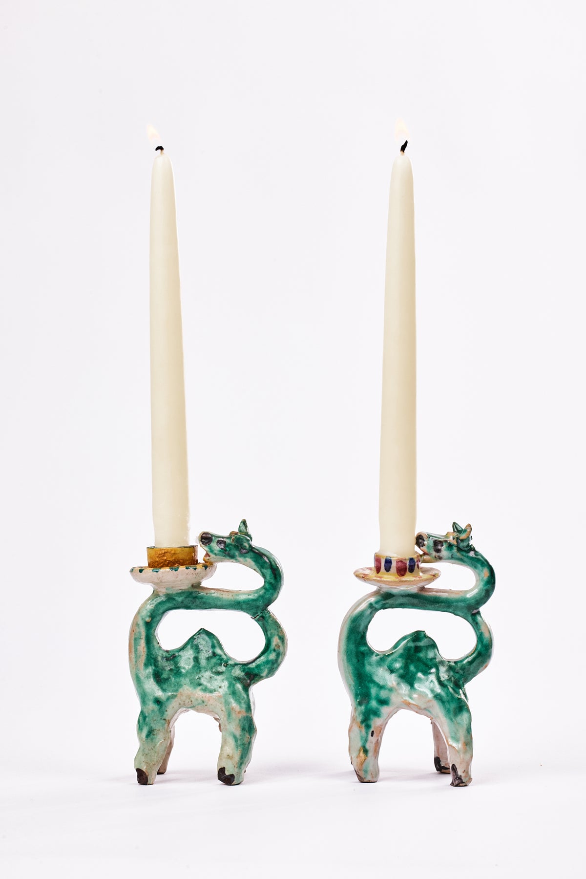 abstract handmade ceramic green-glazed donkey candleholders with off-white unit taper candles.