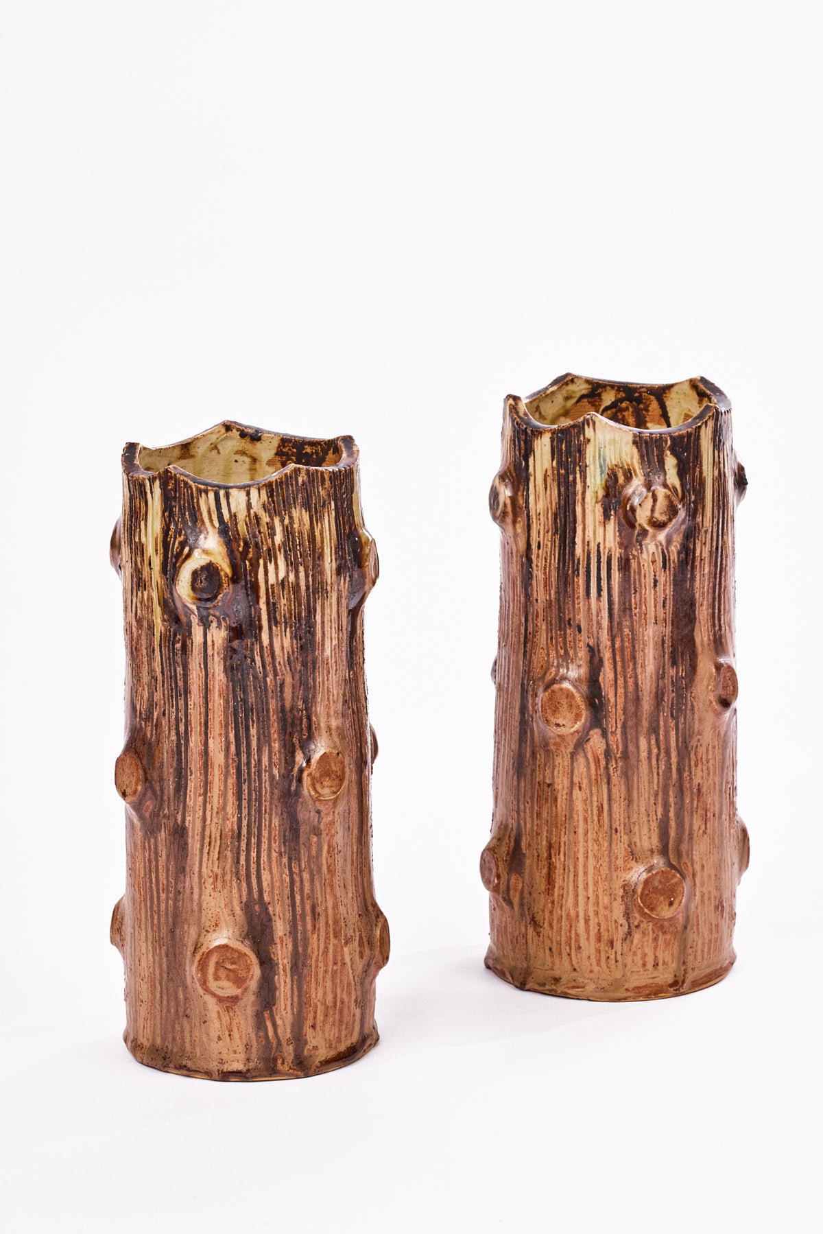 Two ceramic tree trunk vases with textured bark-like detailing and rounded knot accents, shown on a plain white background.
