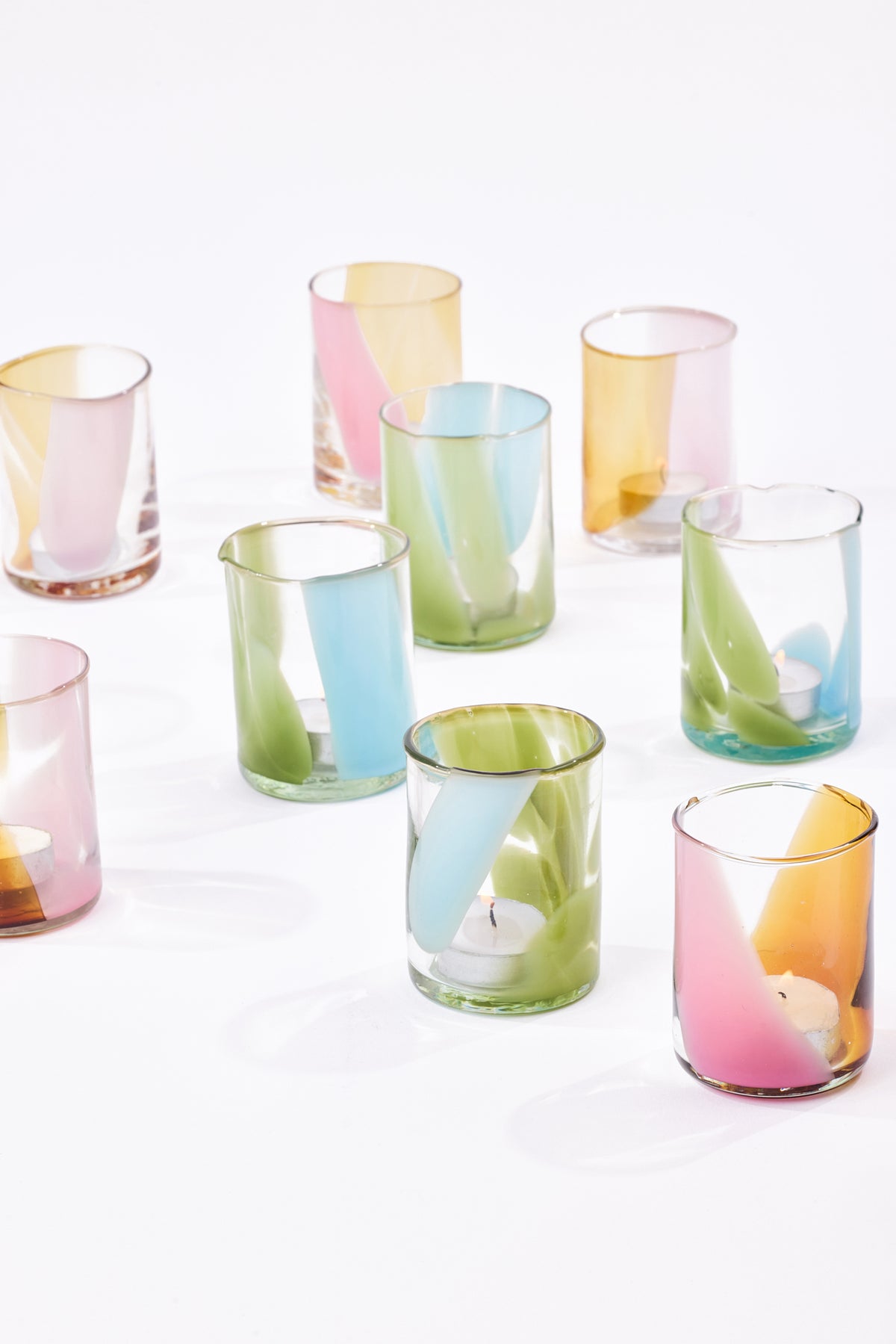 A set of pastel-colored glass candle holders shown on a clean white background.