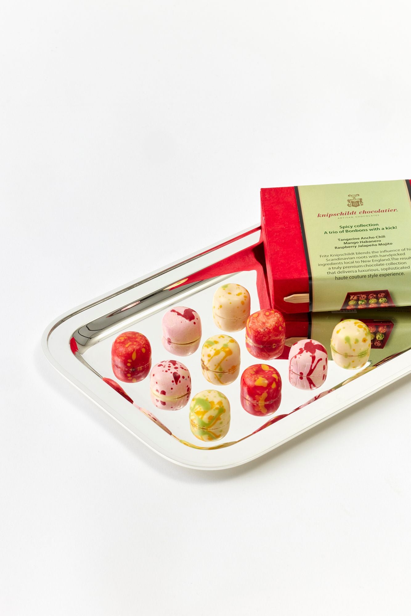 Assorted truffles on a tray with a chocolate brand packaging in the background