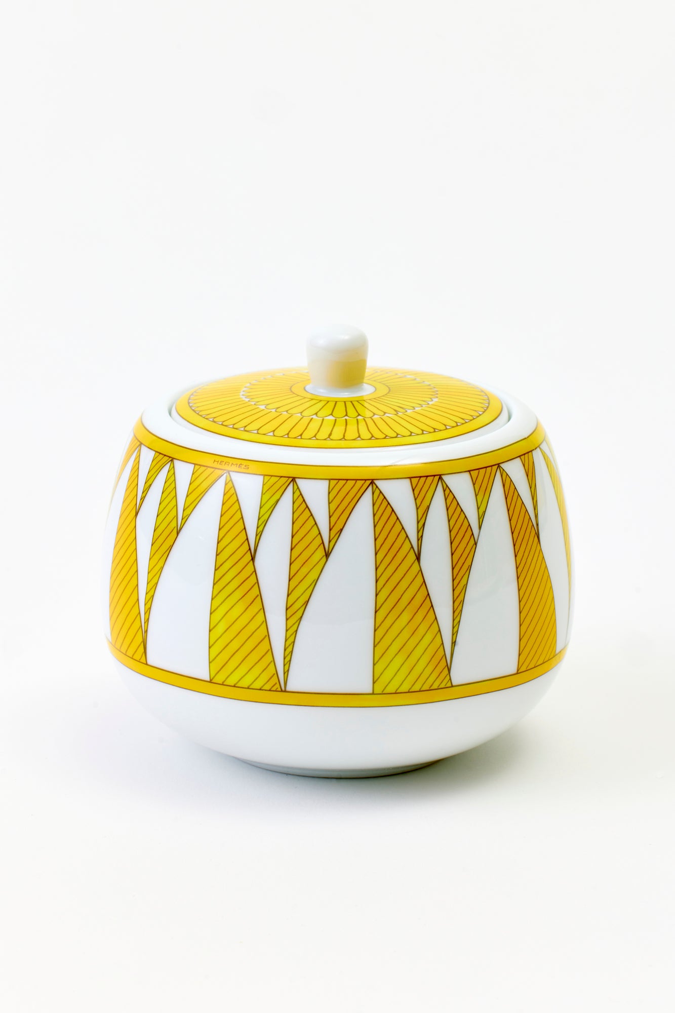 This architectural design by Arielle de Brichambaut for Hermès is intensely ablaze, its graphic forms radiating with warmth. The subtle variation in shades of yellow and the cross-hatched contours give depth to this ode to summer. Convivial, carefree, and even more beautiful in person - just like you. Fine porcelain. Made in France.