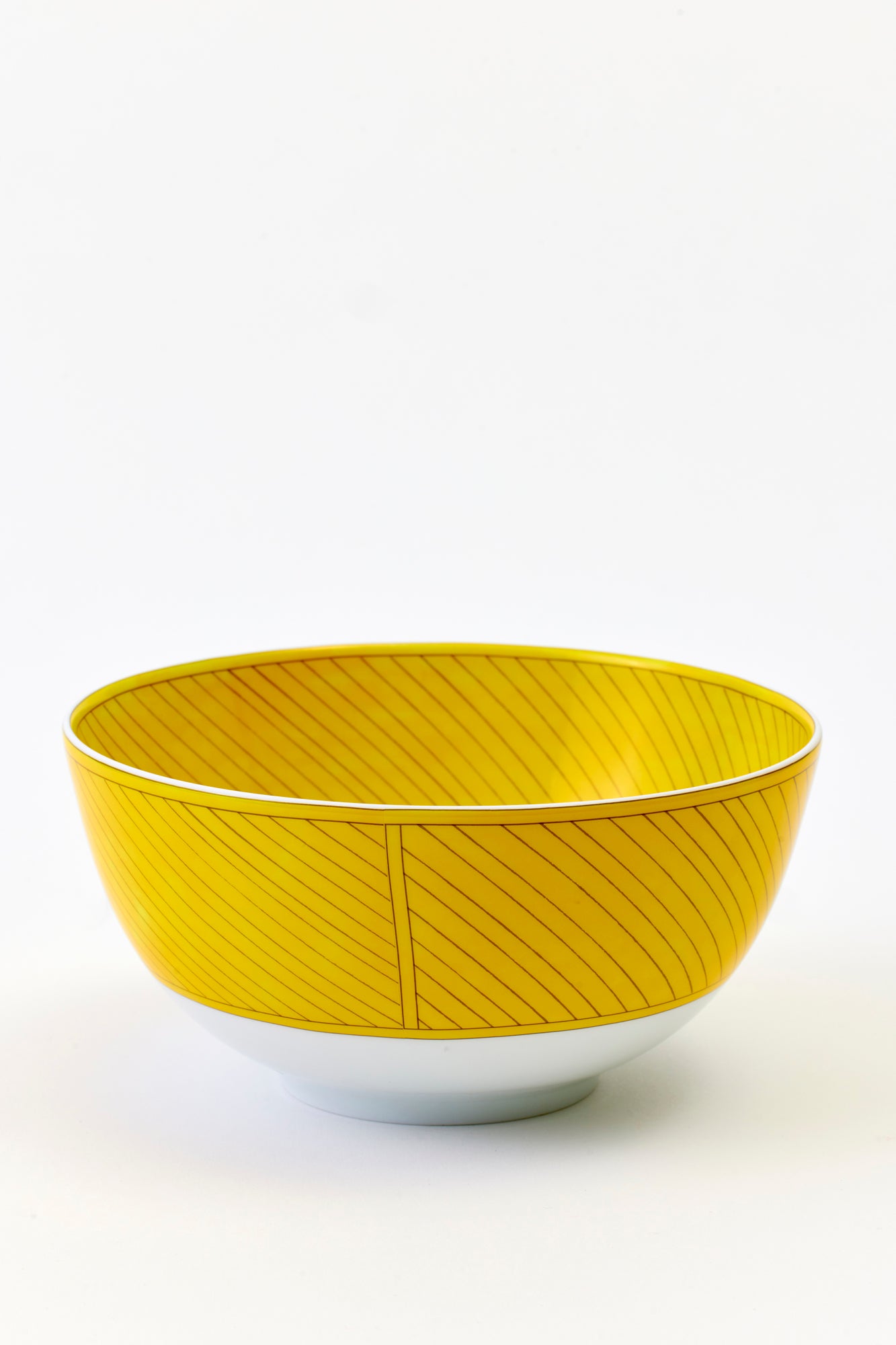 This architectural design by Arielle de Brichambaut for Hermès is intensely ablaze, its graphic forms radiating with warmth. The subtle variation in shades of yellow and the cross-hatched contours give depth to this ode to summer. Convivial, carefree, and even more beautiful in person - just like you. Fine porcelain. Made in France.