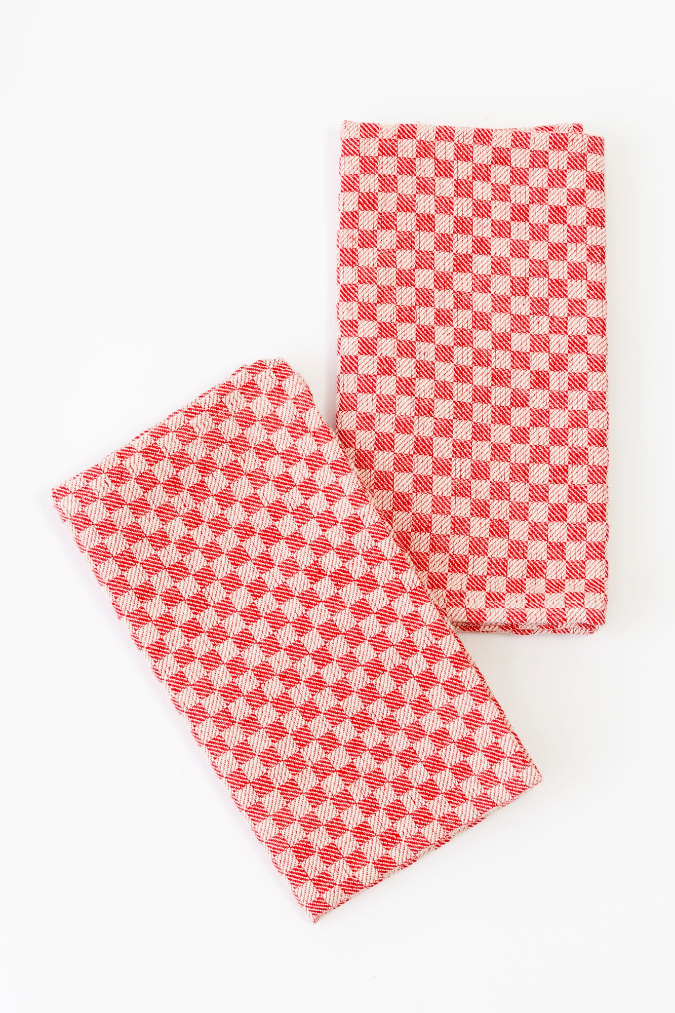 Set of two napkins against a white background. Cotton linen blend napkins featuring a red and white checkered pattern.