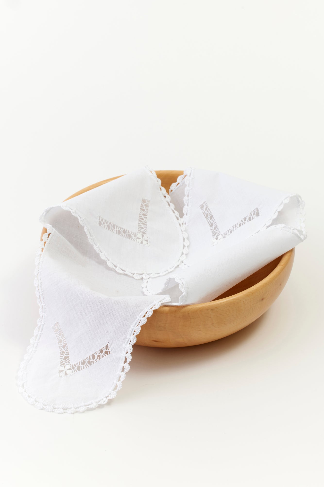 White openwork embroidery linen bread warmer resting inside wood bowl. Perfect for fresh baked holiday gifts.