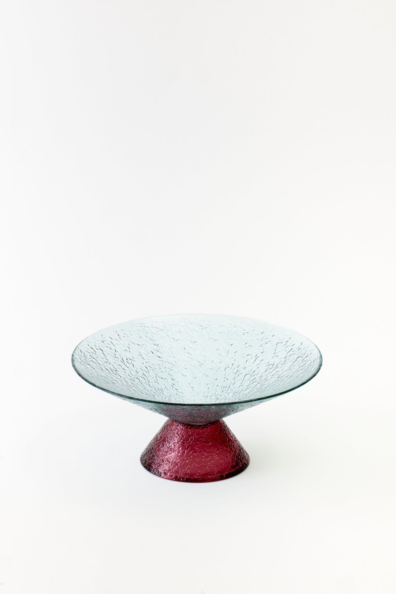Modern glass pedestal dish in a soft rose hue, featuring a textured surface. A striking blend of style and function for chic dining experiences.