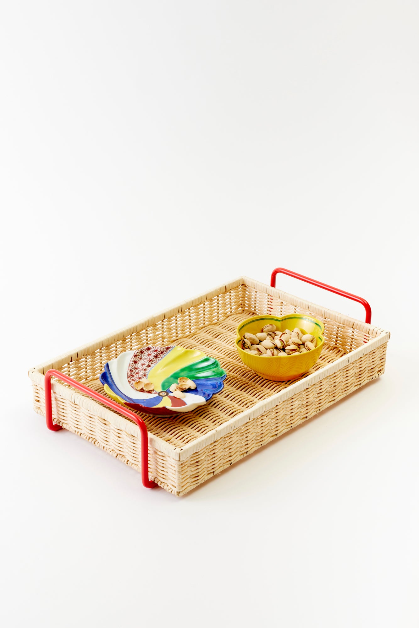 Stylish wicker serving tray with colorful ceramic plates and a yellow snack bowl. A blend of rustic charm and modern flair for entertaining and serving.