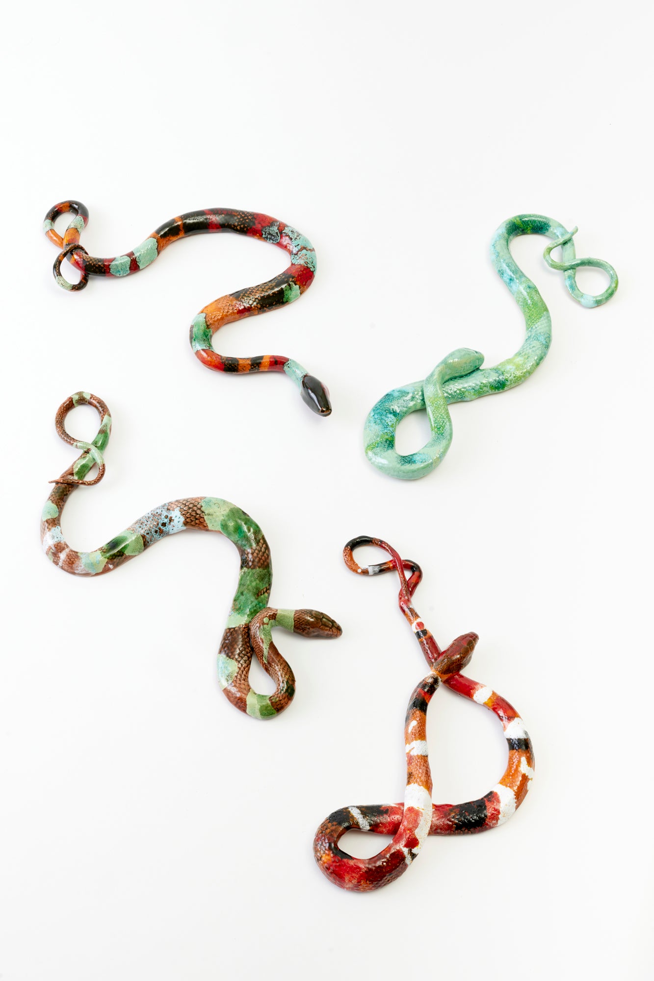 4 ceramic snakes against a white background.