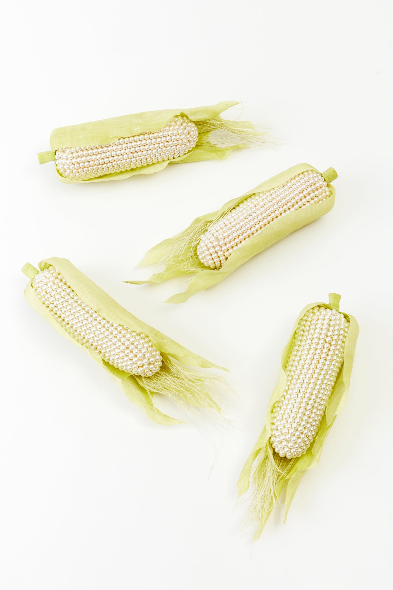 Luxurious ears of corn crafted from radiant pearls, encased in soft, pale green husks. This artful take on nature’s bounty blends opulence with whimsical elegance—perfect for the fashion-forward home.