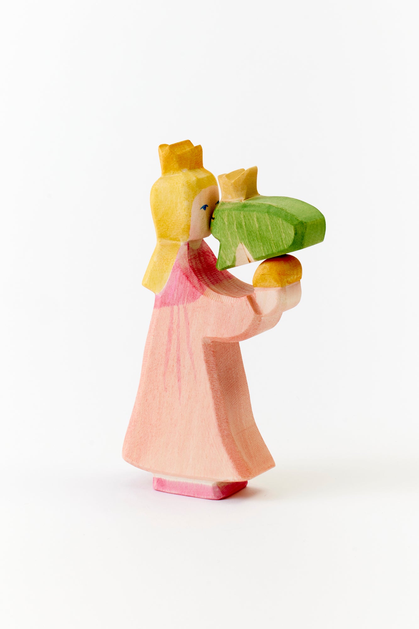 A storybook moment frozen in wood: a crowned princess leans in to kiss her green frog prince, capturing a fairytale kiss with handcrafted elegance.