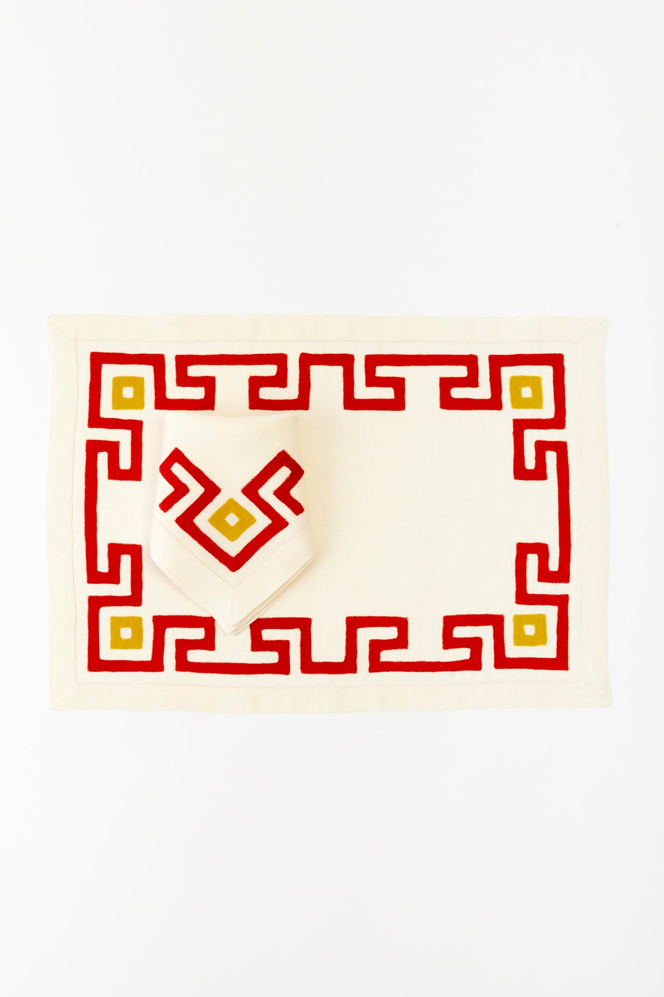 Cream linen napkin and placemat set with bold red and yellow geometric embroidery, perfect for modern table settings.