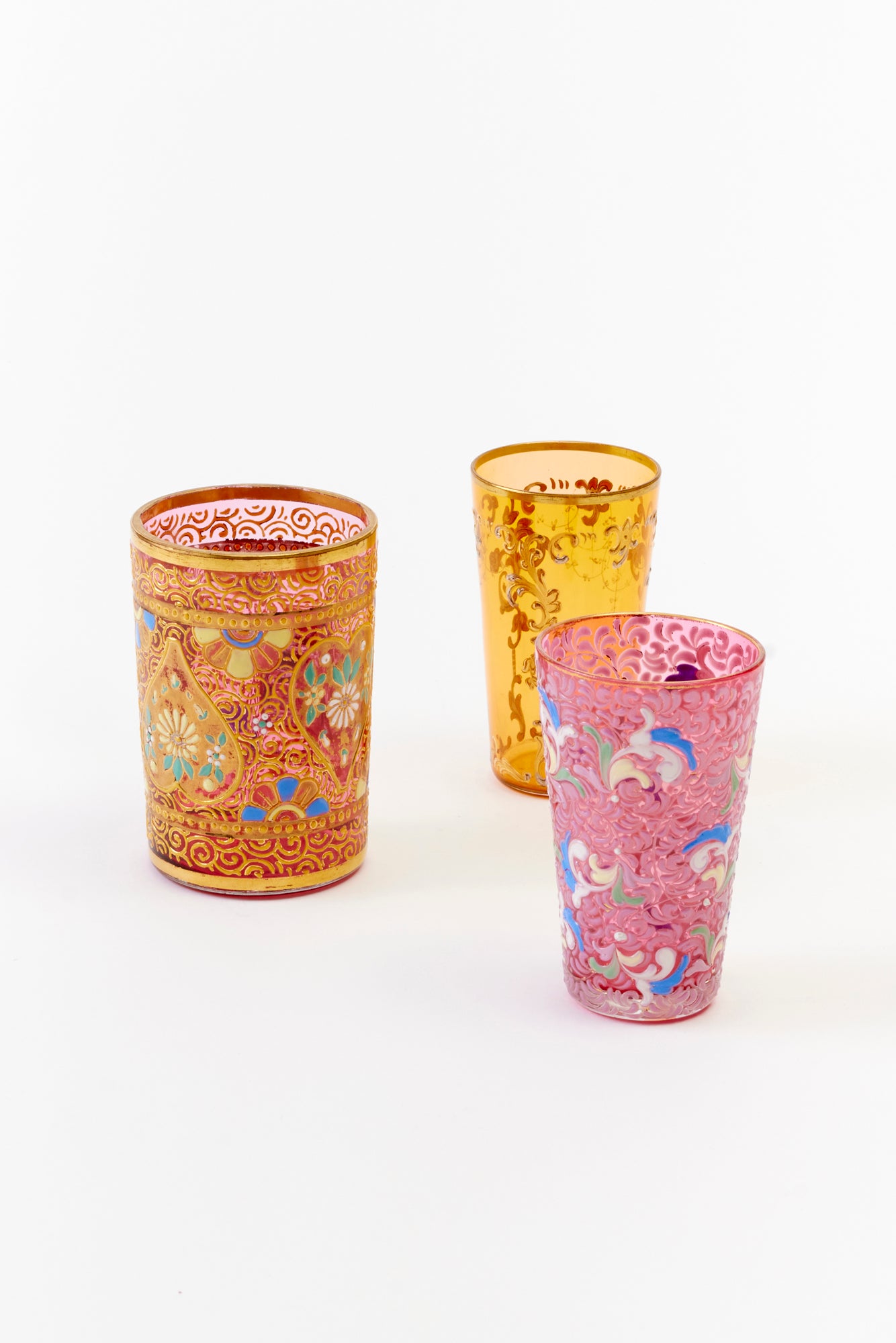 Set of three ornate vintage Japanese glasses in gold, yellow, and pink with intricate floral patterns.