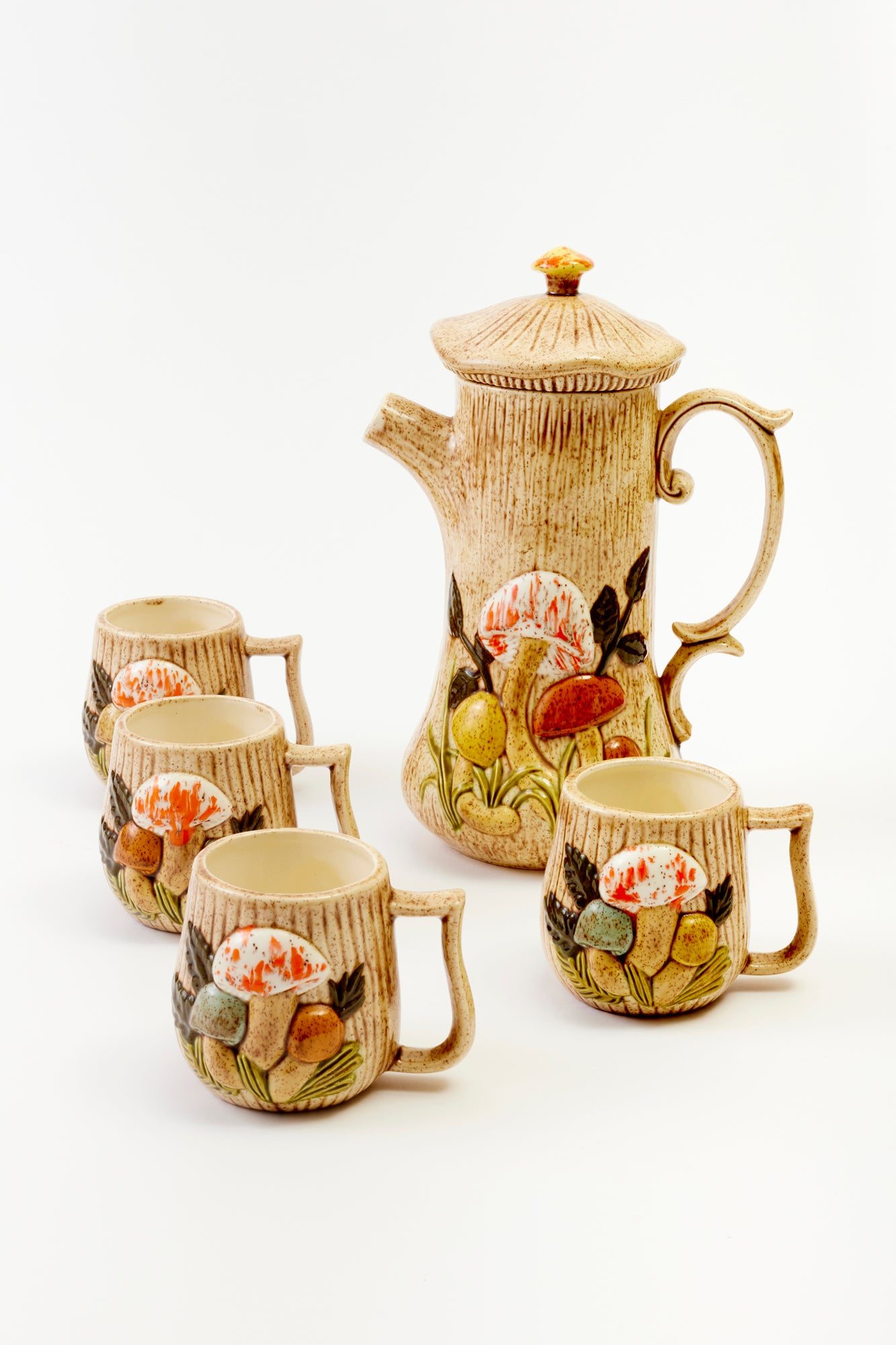 Vintage-style ceramic teapot with mushroom and floral motifs, accompanied by four matching mugs.