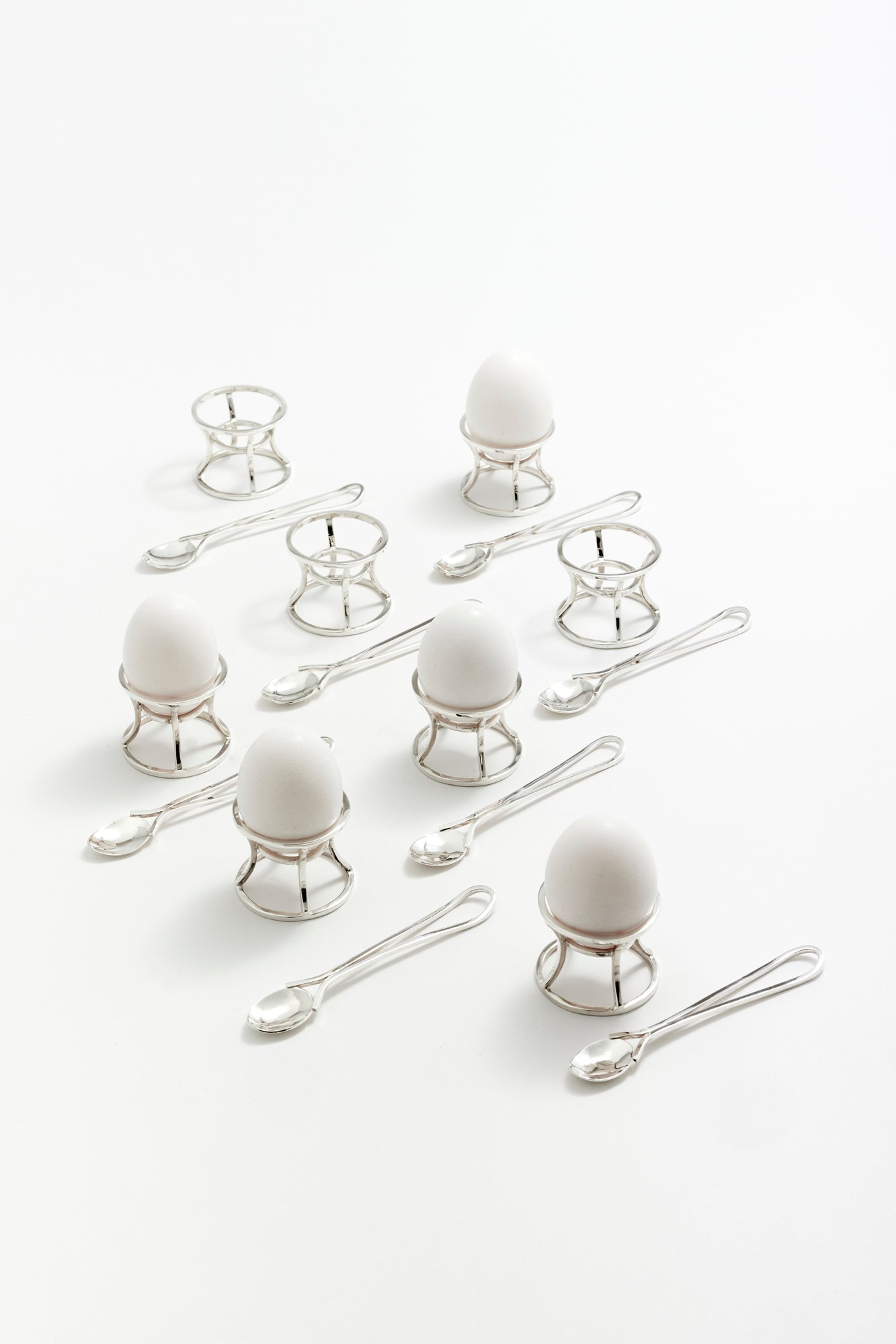 Architectural silver egg holders with matching spoons and boiled eggs, offering an elevated breakfast presentation. A sophisticated addition to your table setting.