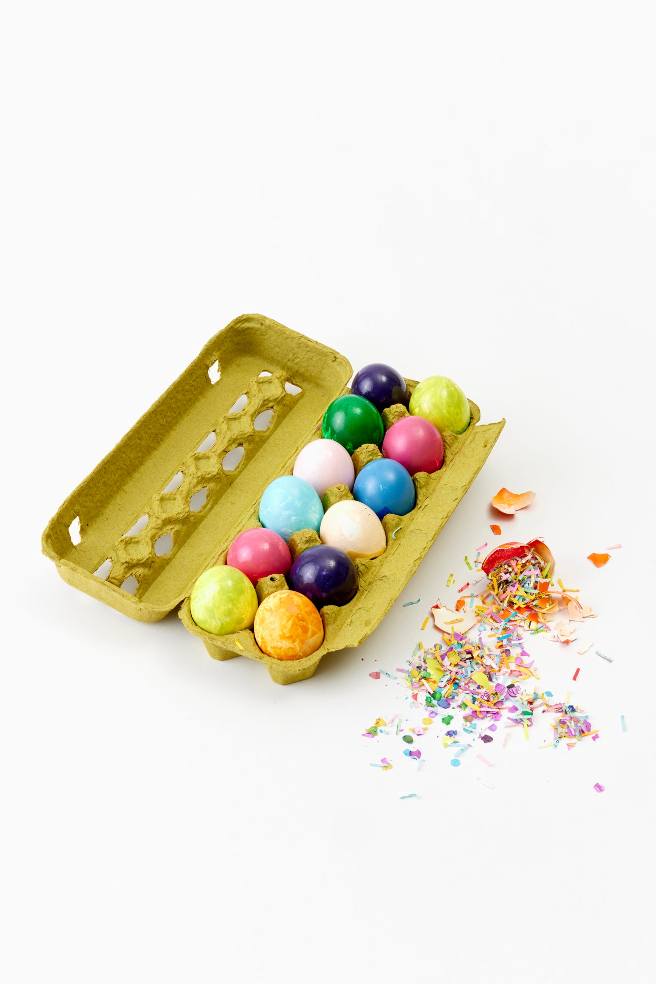Carton of a colorful dozen eggs with confetti in them.