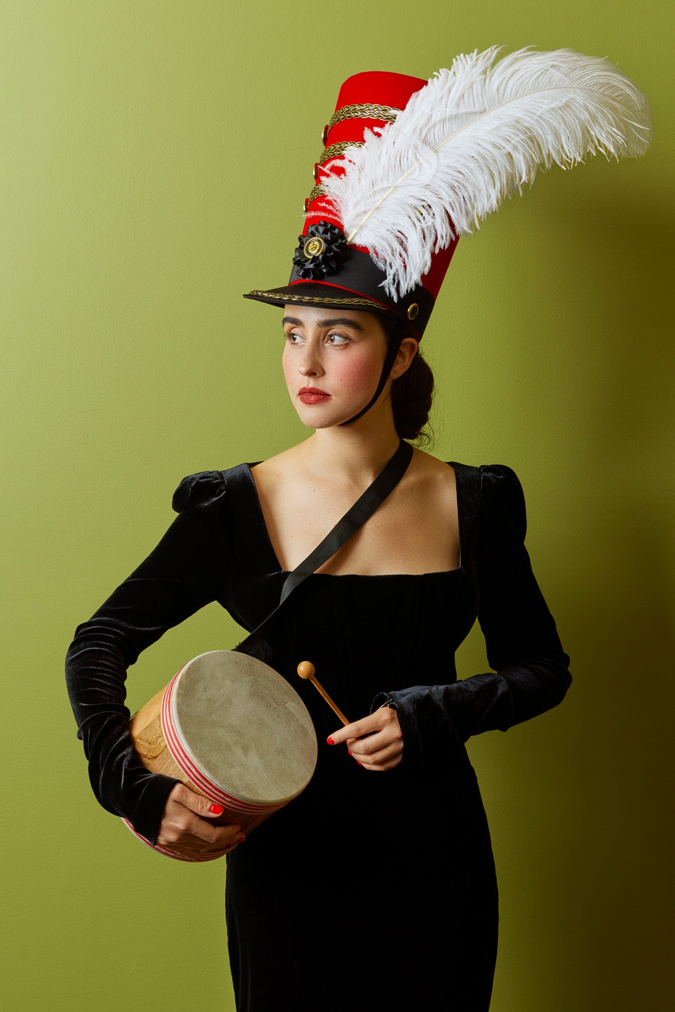 Drum major hat that is tall and red.