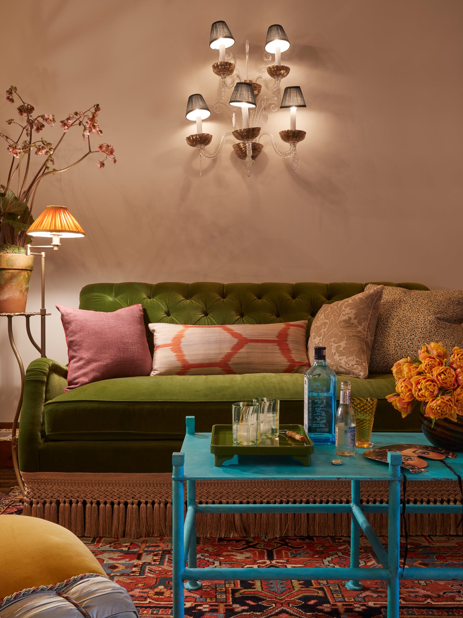 Eclectic vintage-style living room with green velvet chairs, blue table.