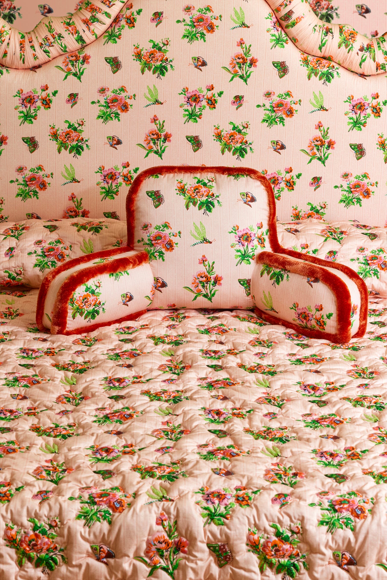 Pink chintz husband pillow with matching headboard and quilted coverlet.