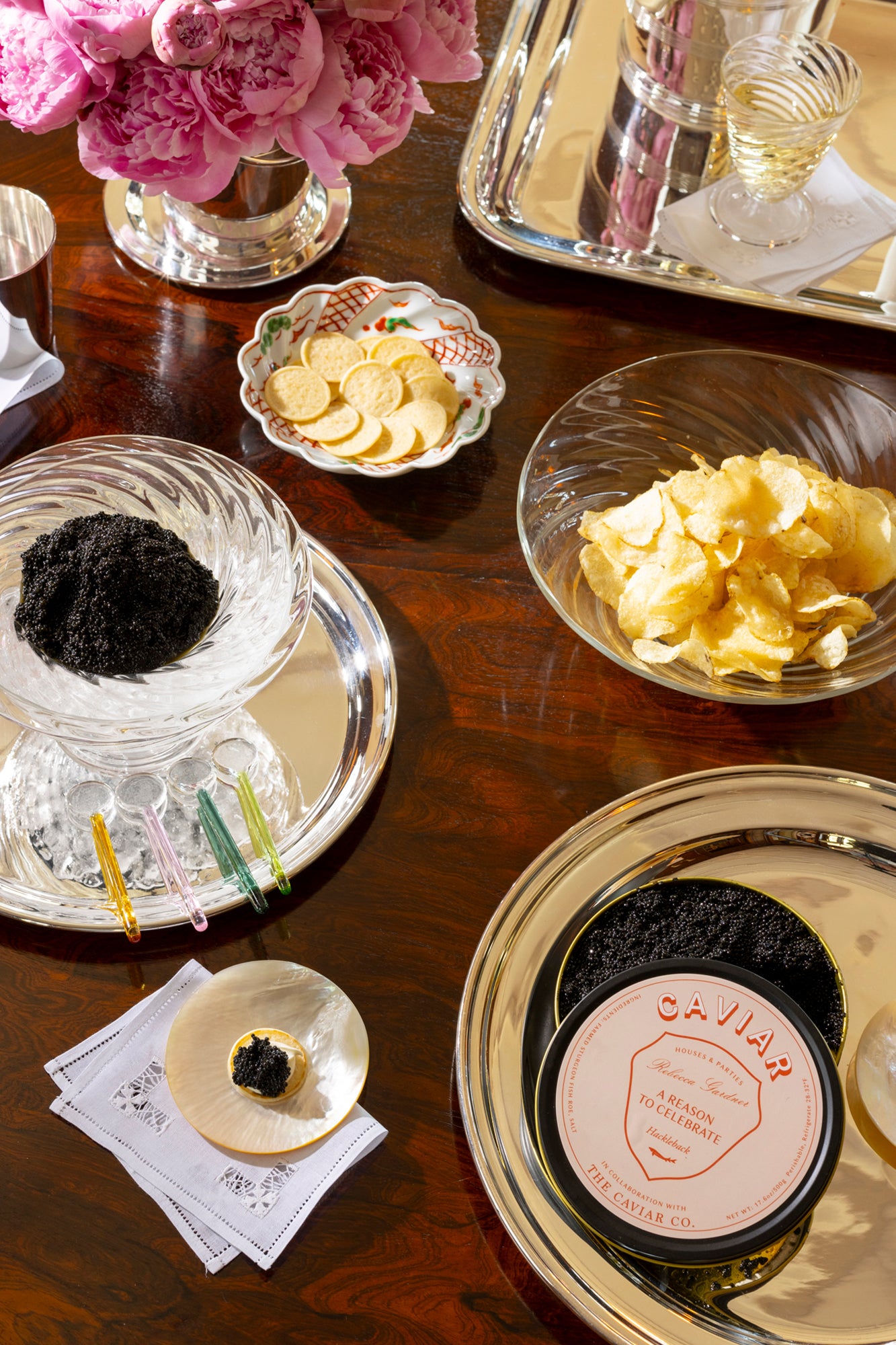 Party-sized artisanal twisted handblown glass caviar service, filled with black caviar and resting on a silver platter with glass caviar spoons.