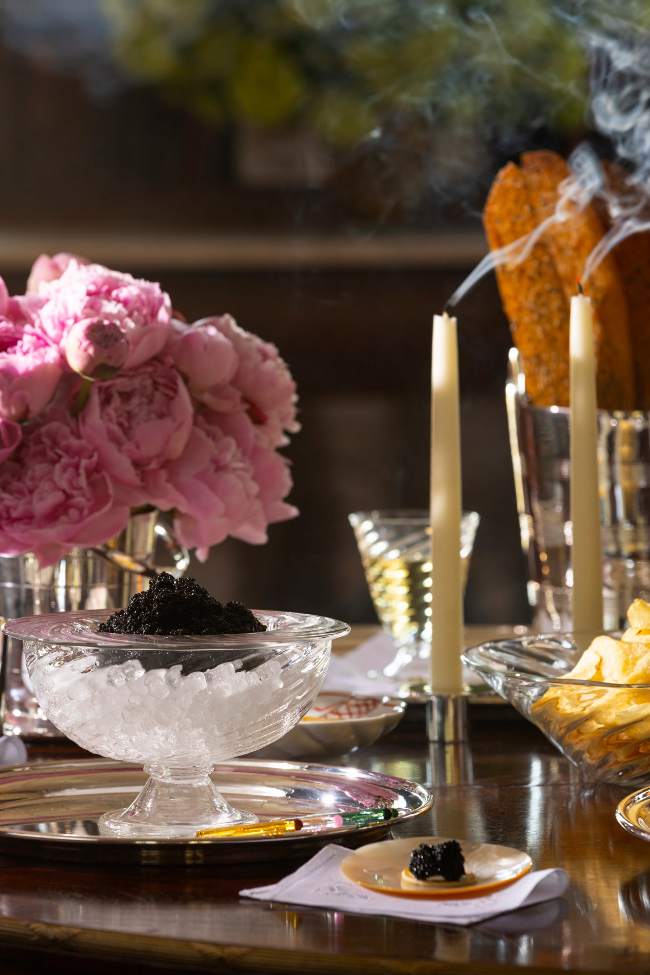Party-sized artisanal twisted handblown glass caviar service, filled with black caviar and resting on a silver platter with glass caviar spoons.