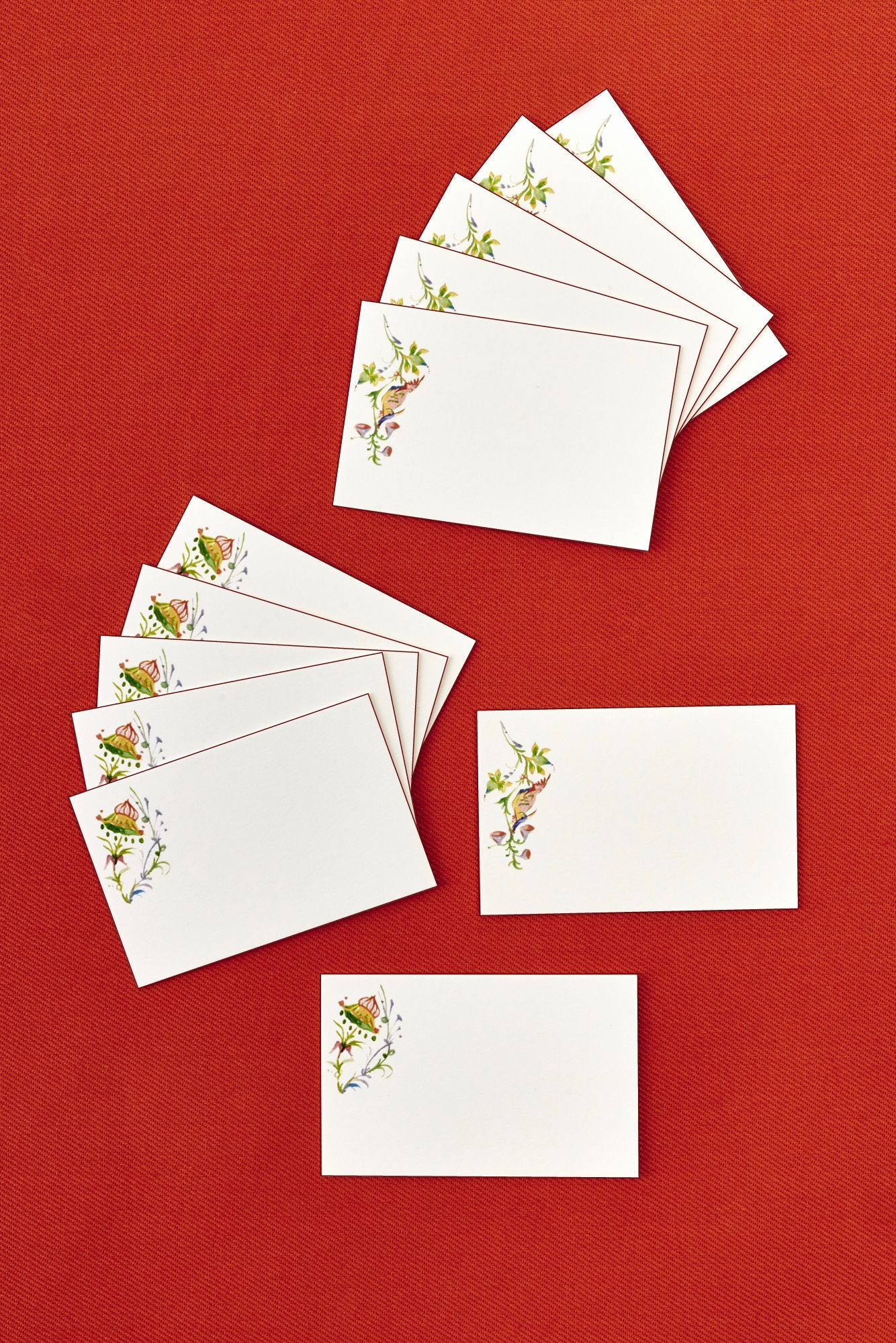 Set of white cards with floral designs on a red background