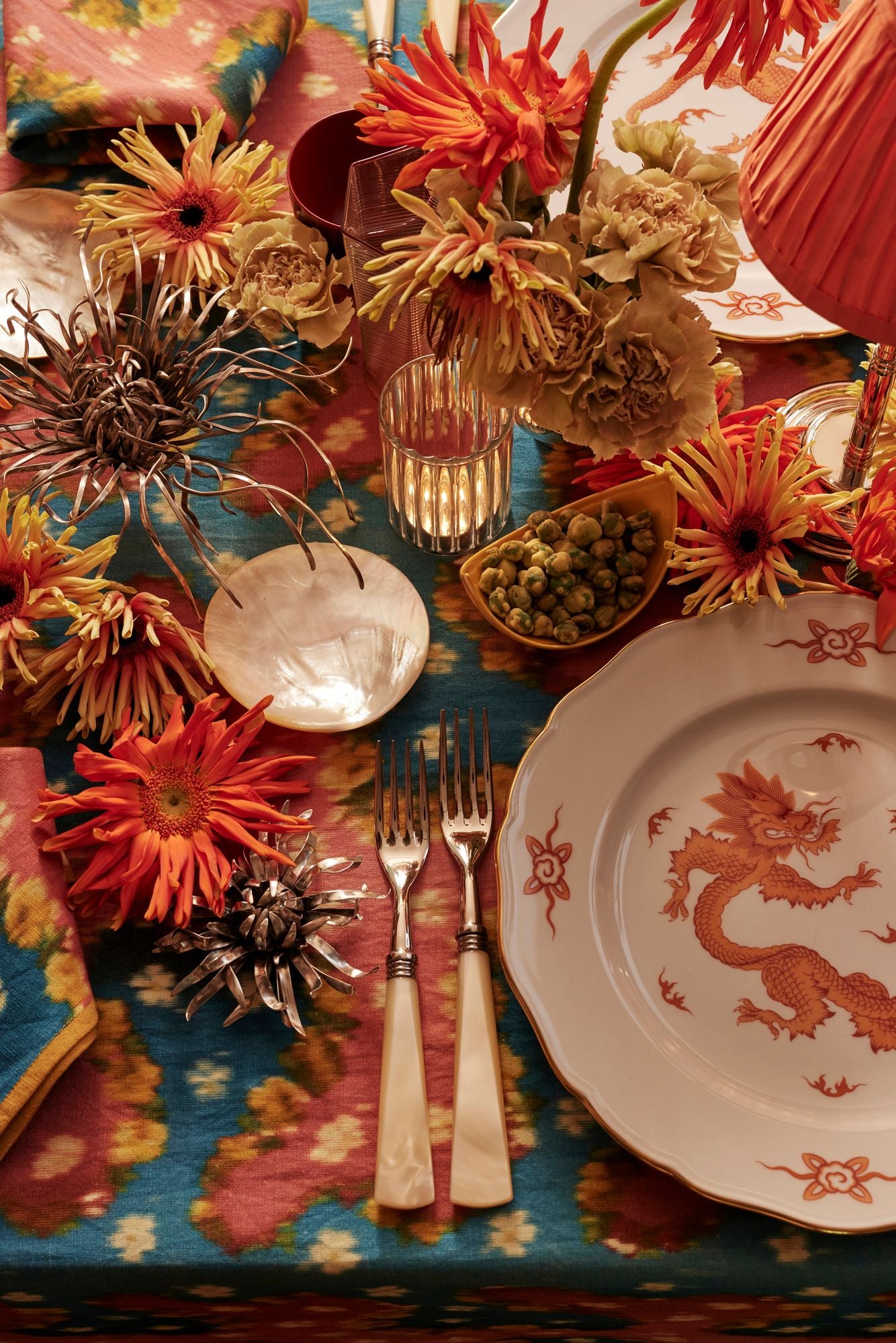 Decorative table setting with floral arrangements, plates, and cutlery on a colorful tablecloth.