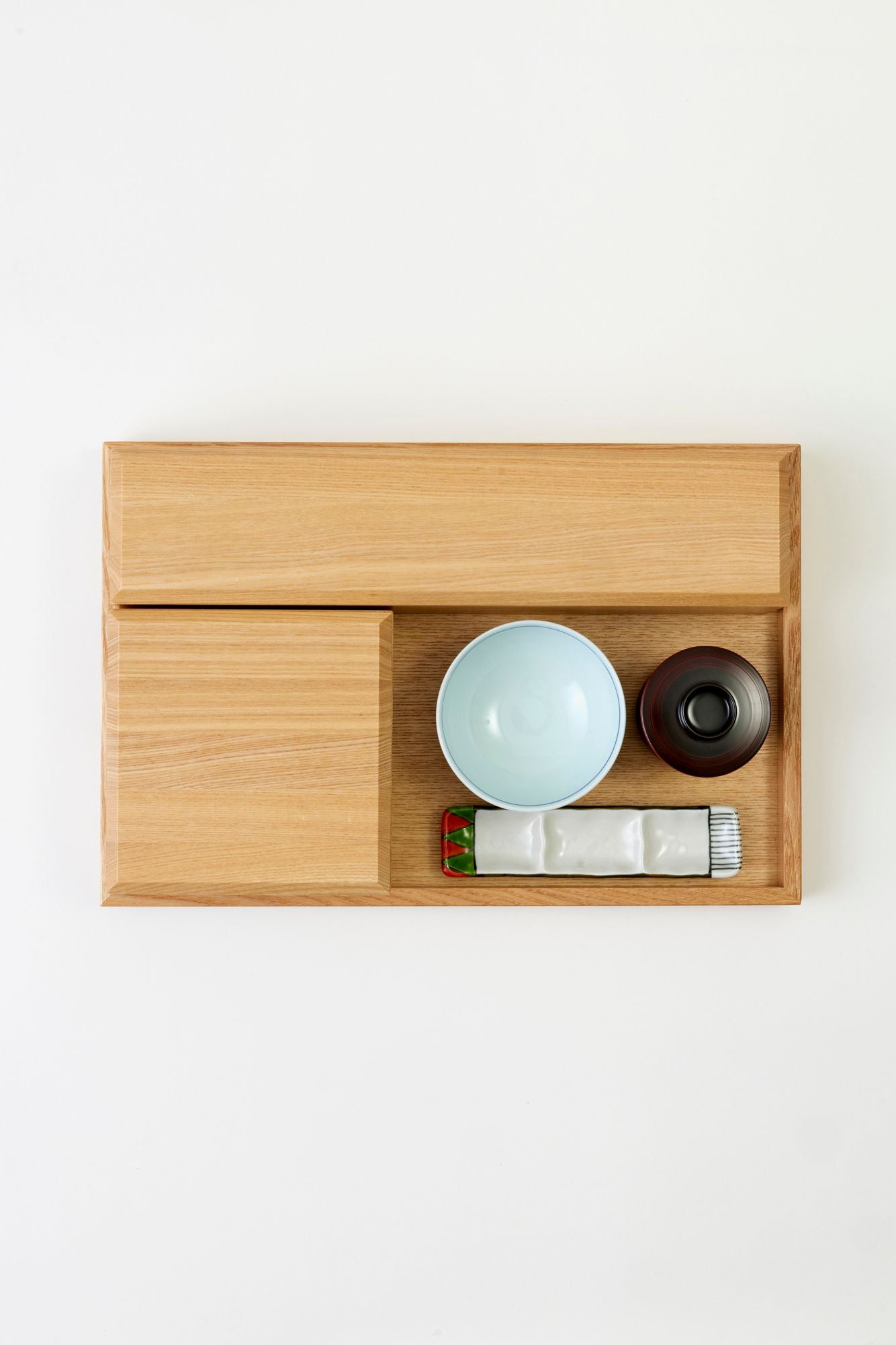 Wood bento box with Japanese ceramic dishes on a white tablecloth