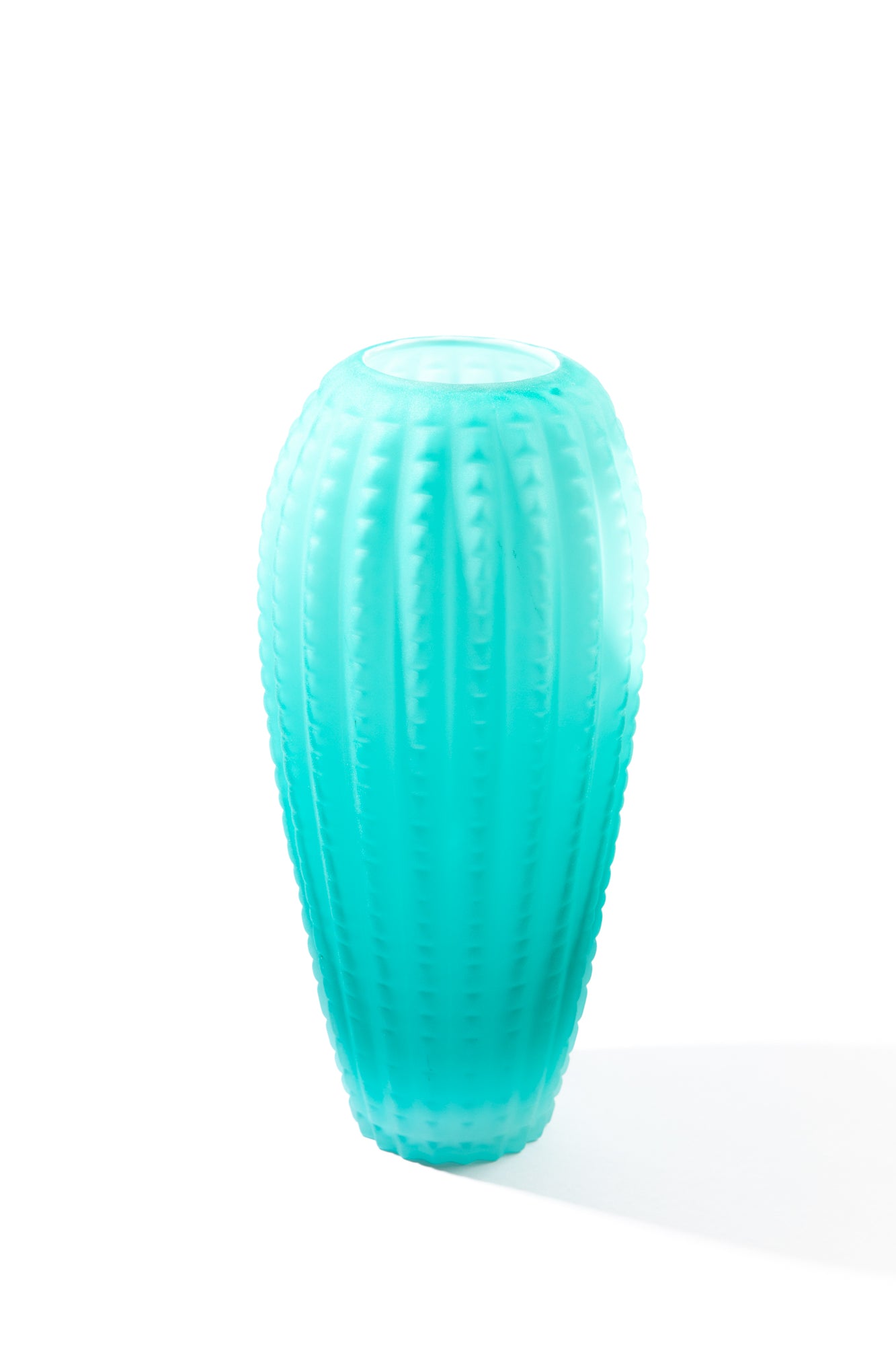 Blue vintage vase against white background. Frosted teal glass with a ribbed pattern around.