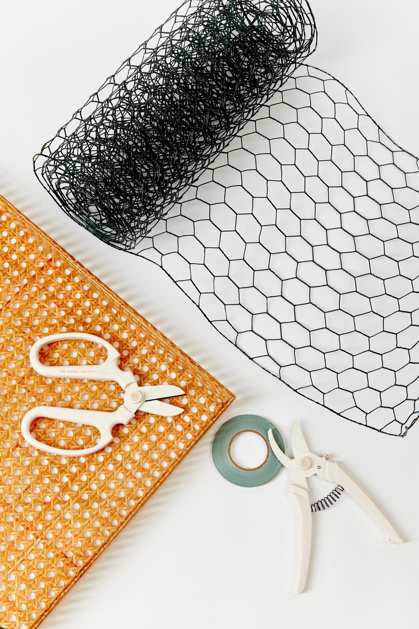 The essential tools for creating floral arrangements: floral netting, tape and scissors.