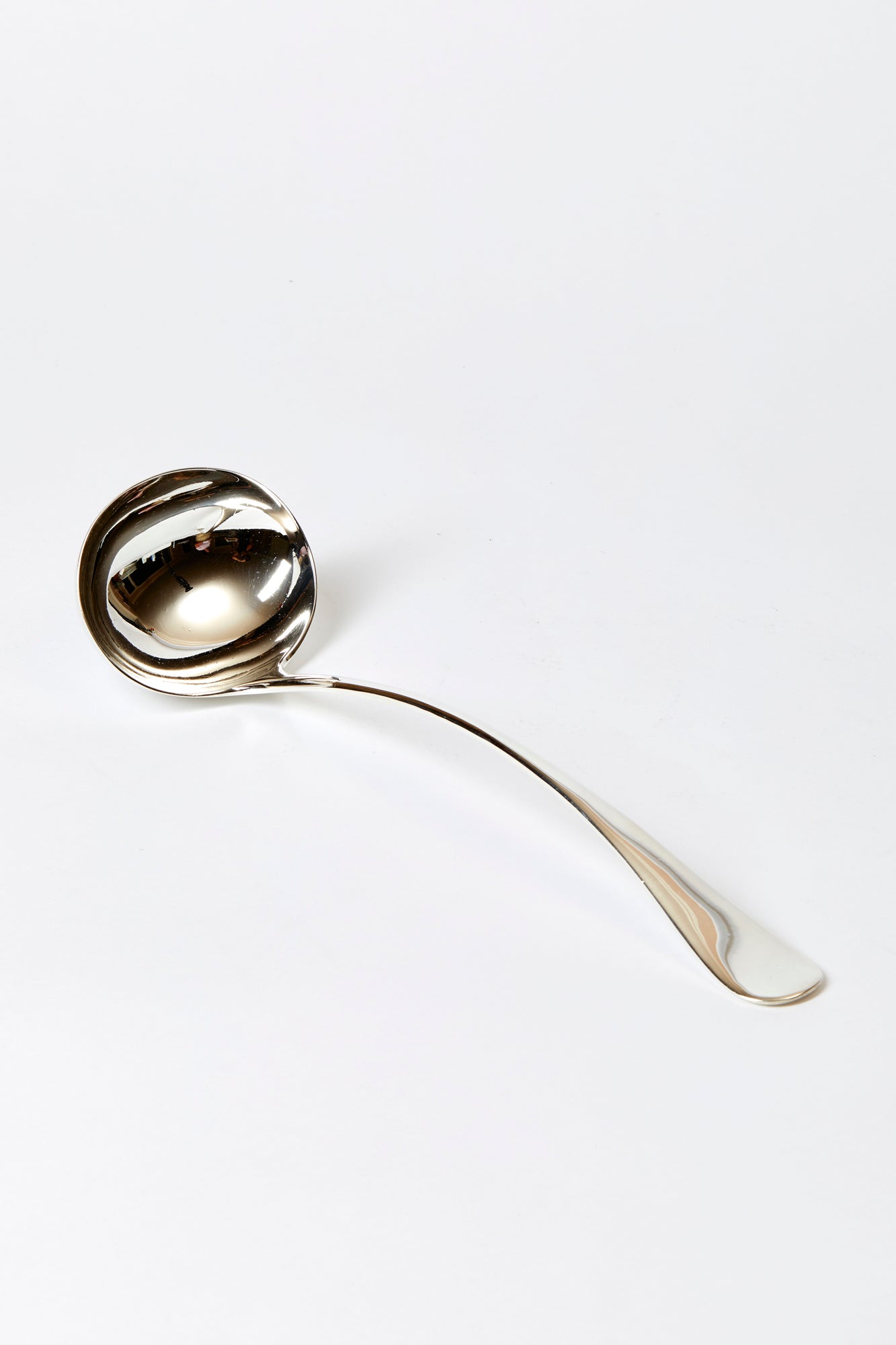 Vintage silver soup ladle against a white background.