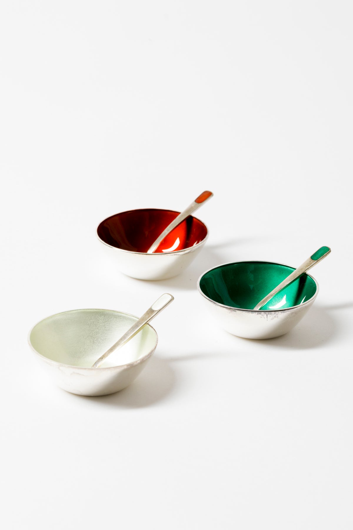 Three silver and enamel salt cellars and spoons.