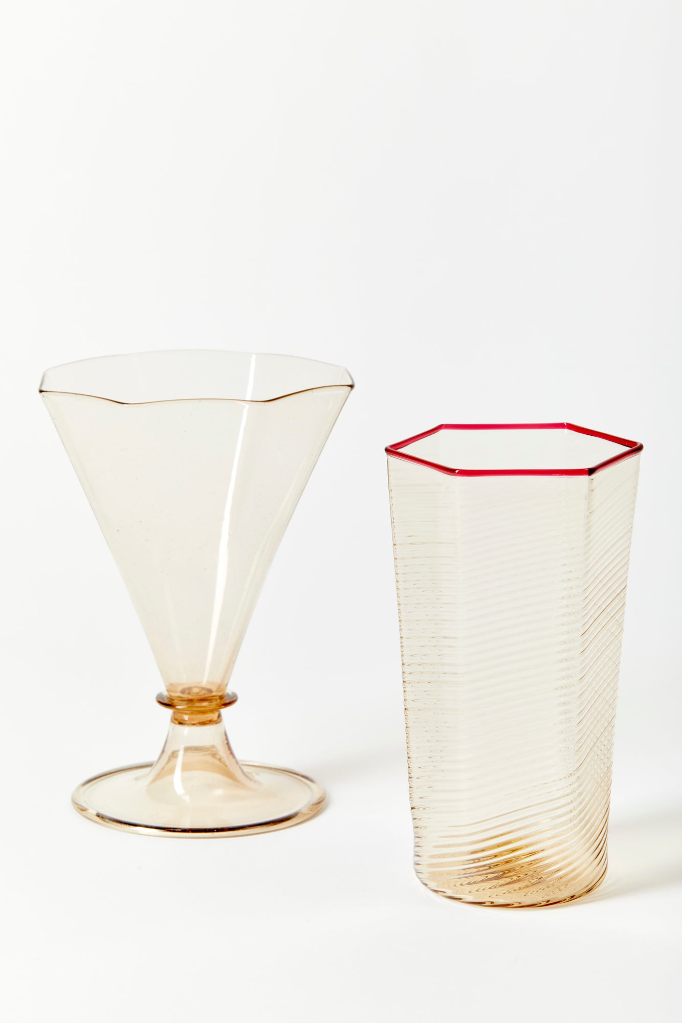 Fine and delicately striated hexagonal glass for everyday use. Handblown and molded by artisans in Murano. The neutral warm smoke color complements the thin red rim.