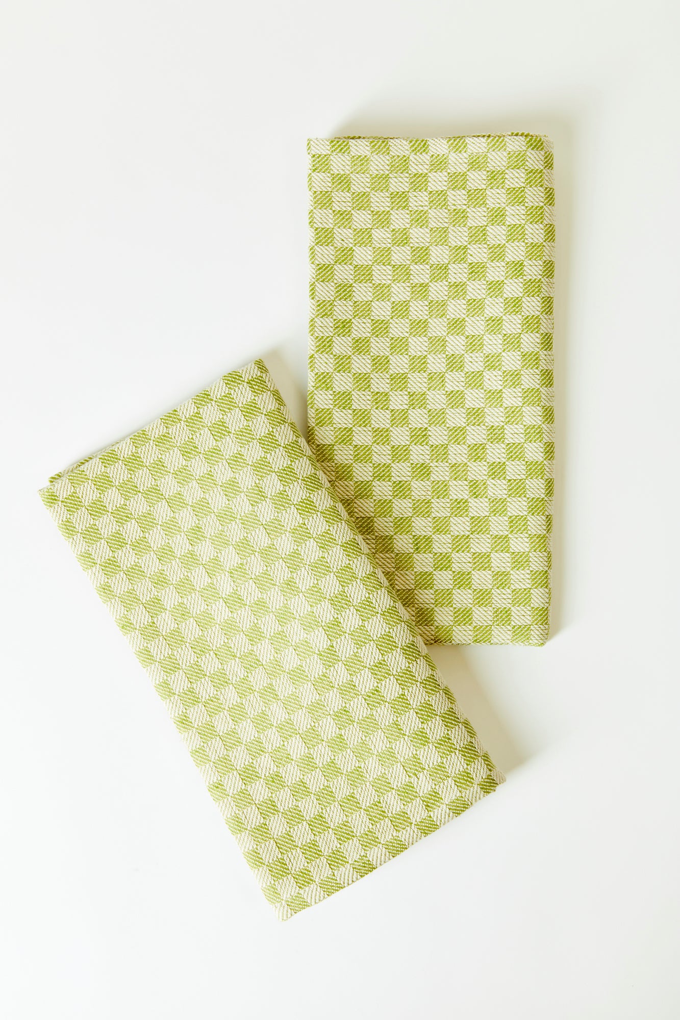 Set of two napkins against a white background. Cotton linen blend napkins featuring a green and white checkered pattern.