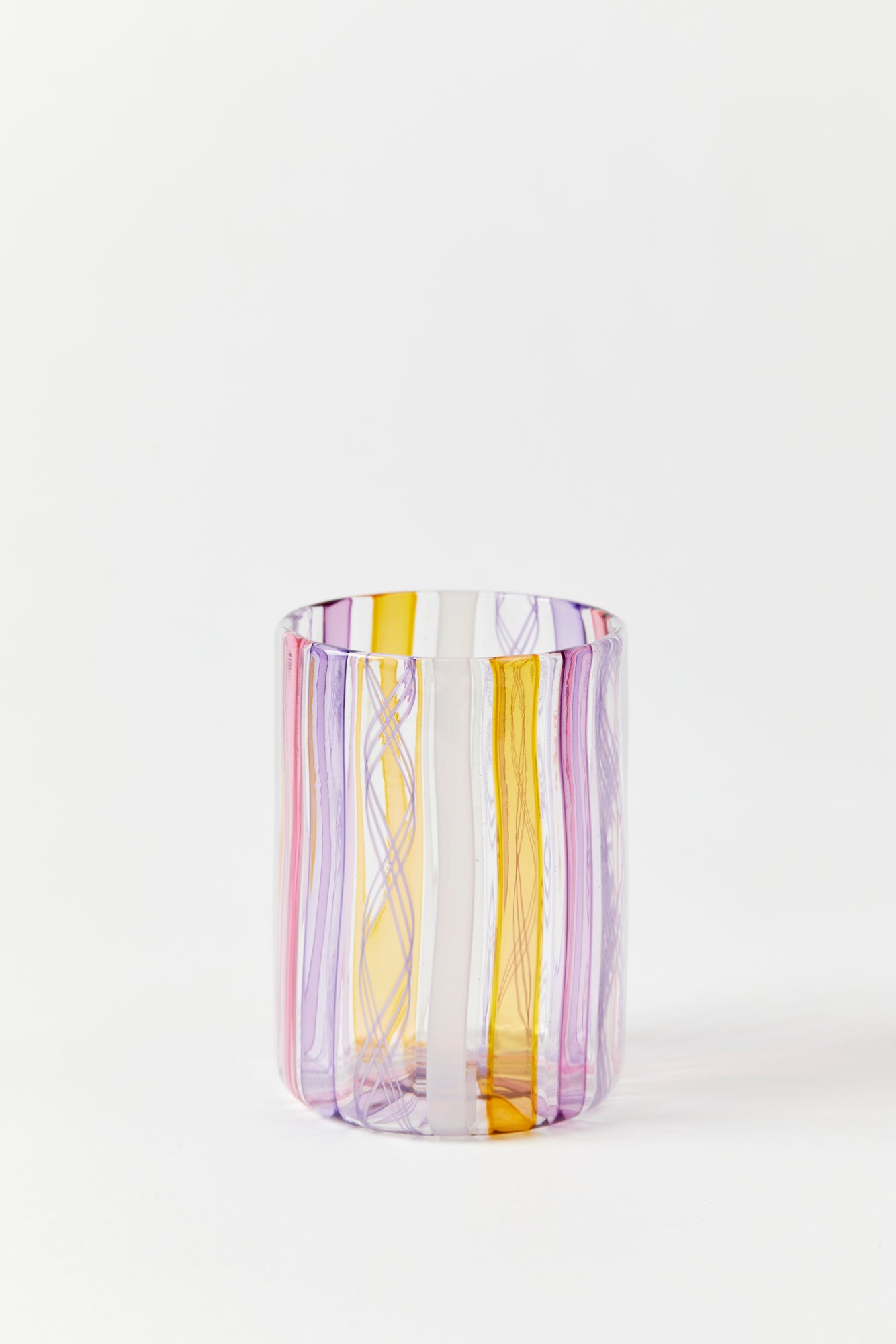 Hand blown tumbler style glass with vertical stripes of pink, purple, yellow, and white.