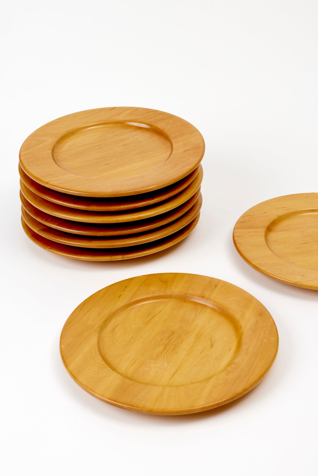 Stack of 6 plates with 2 plates to the side, against a white background. Plates are made of blonde-colored wood and have a 12.13 diameter and are 1.25” in height.