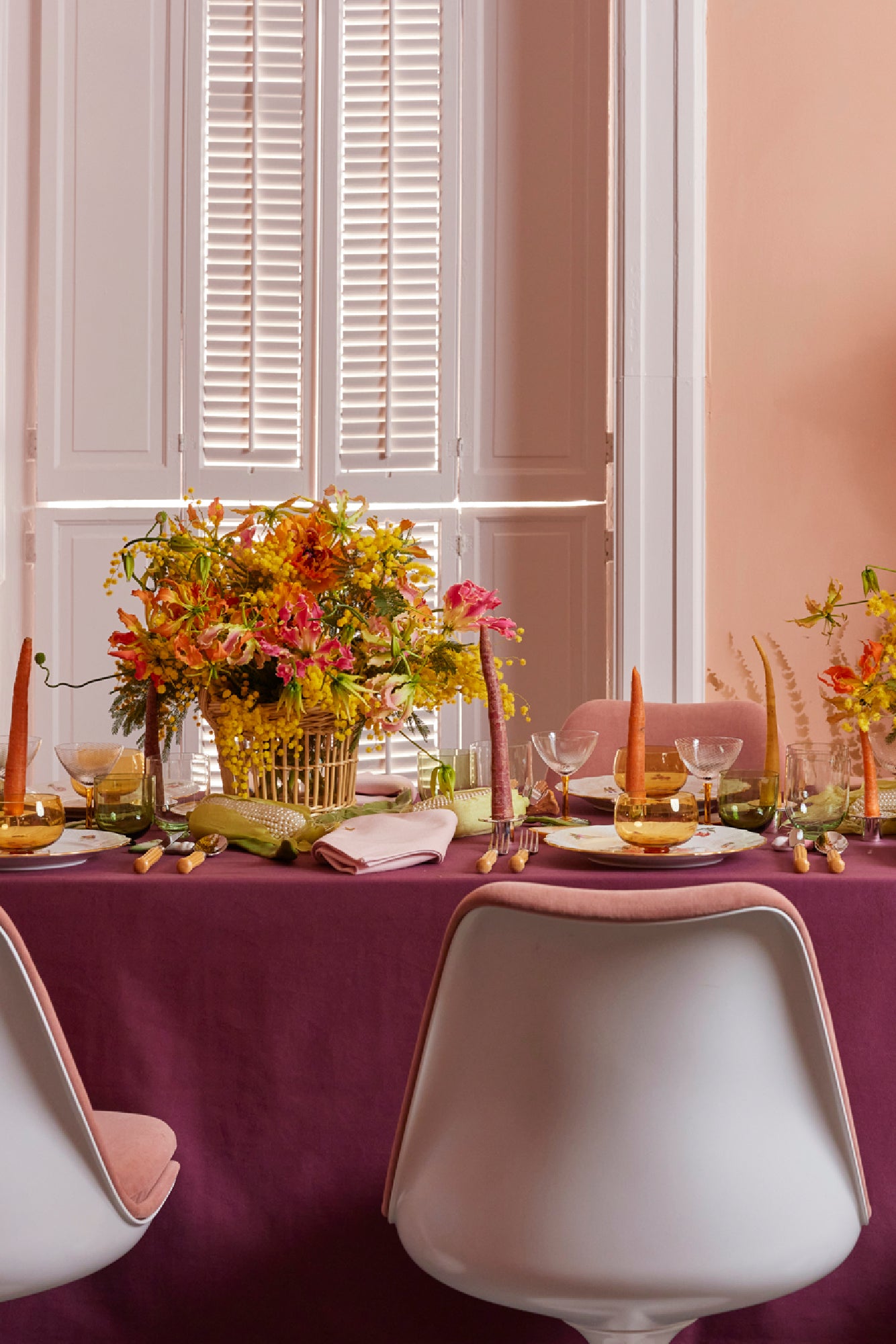 Lively Spring table scape with color block tablecloth in eggplant, bamboo flatware, carrot taper candles, Nason Moretti coupe glass and 3 piece bowl, wine glass and water glass set.