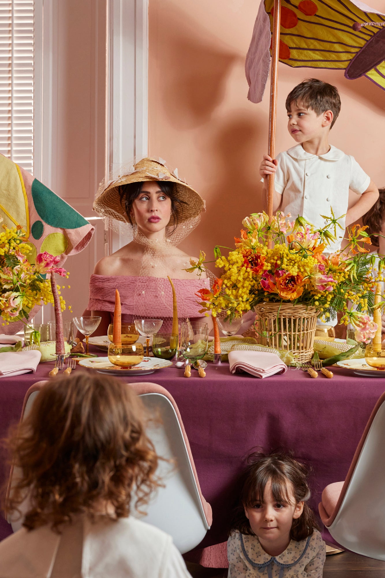 Lively Spring table scape with color block tablecloth in eggplant, carrot taper candles, Nason Moretti coupe glass and 3 piece bowl, wine glass and water glass set.