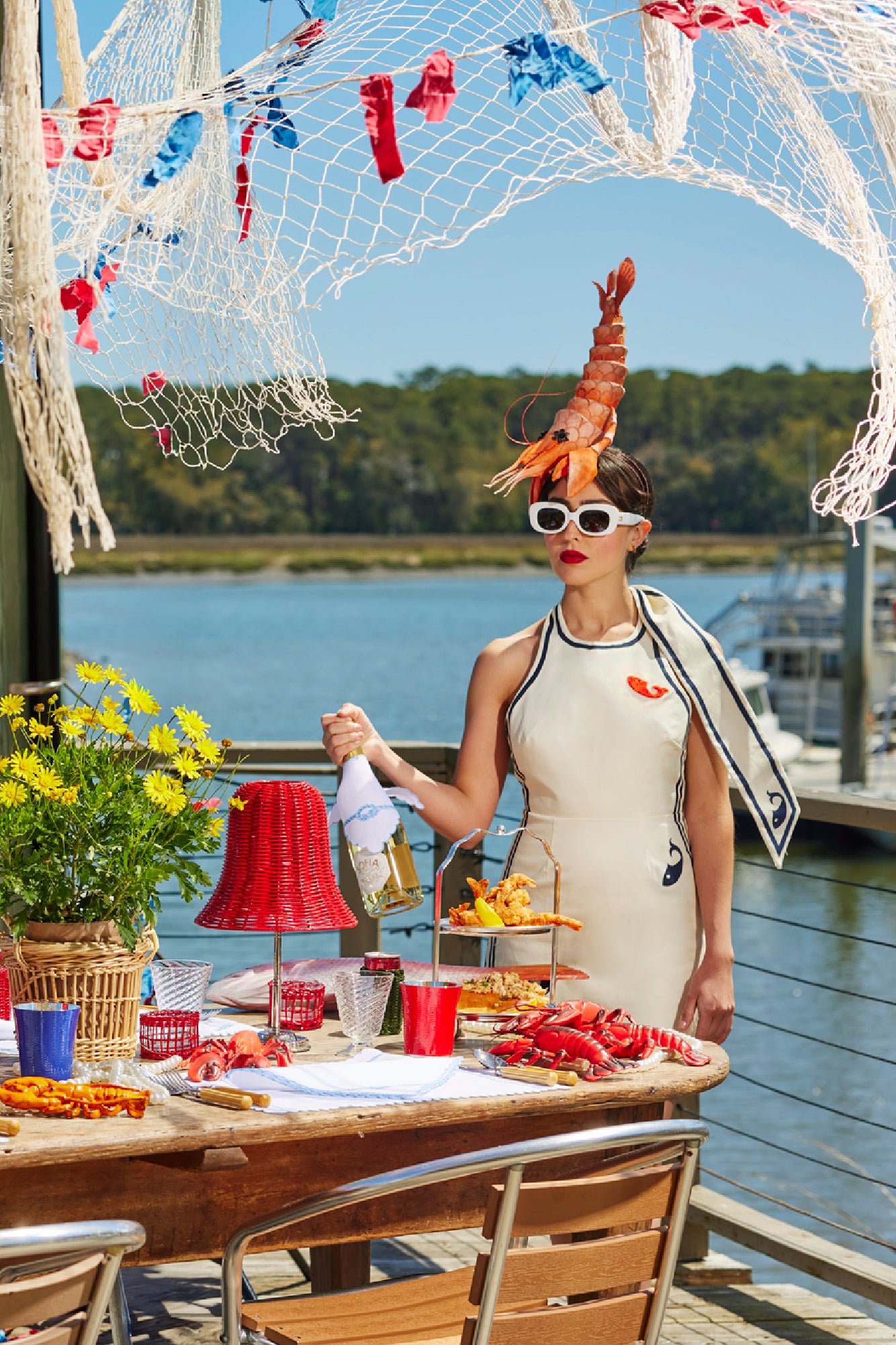 Summer tablescape with wicker lampshade, wicker basket, ceramic lobsters, and silver tea stand.