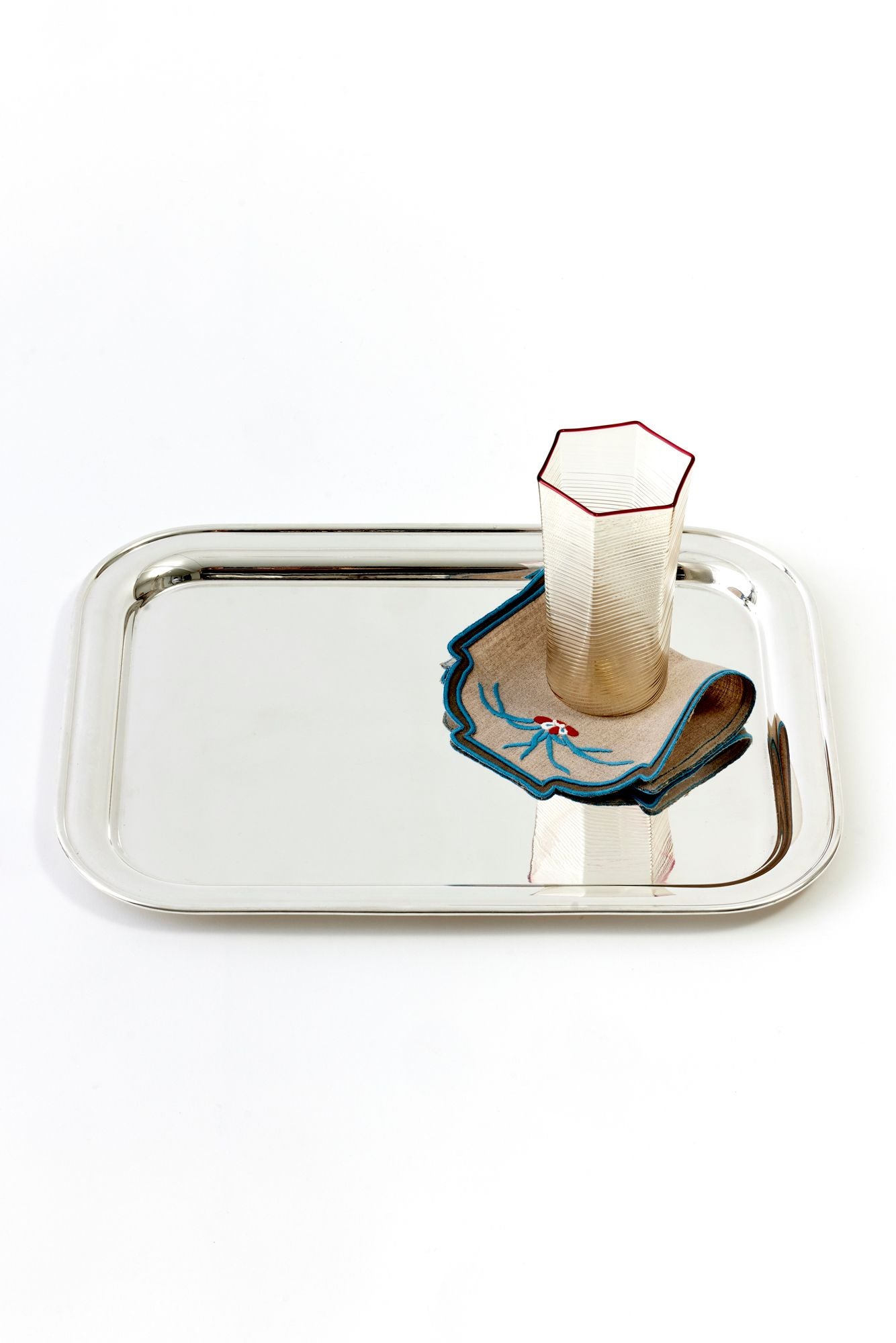 Vintage silver passing tray holding a glass and cocktail napkin on a white background.