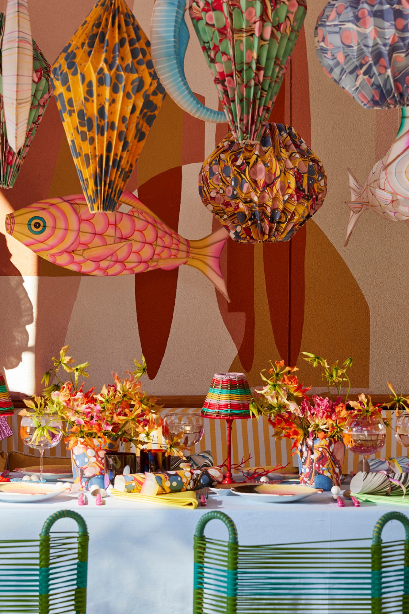 Under the Sea tablescape with marbled party crackers, color-block linens, woven lamp shade, and hot pink flatware.