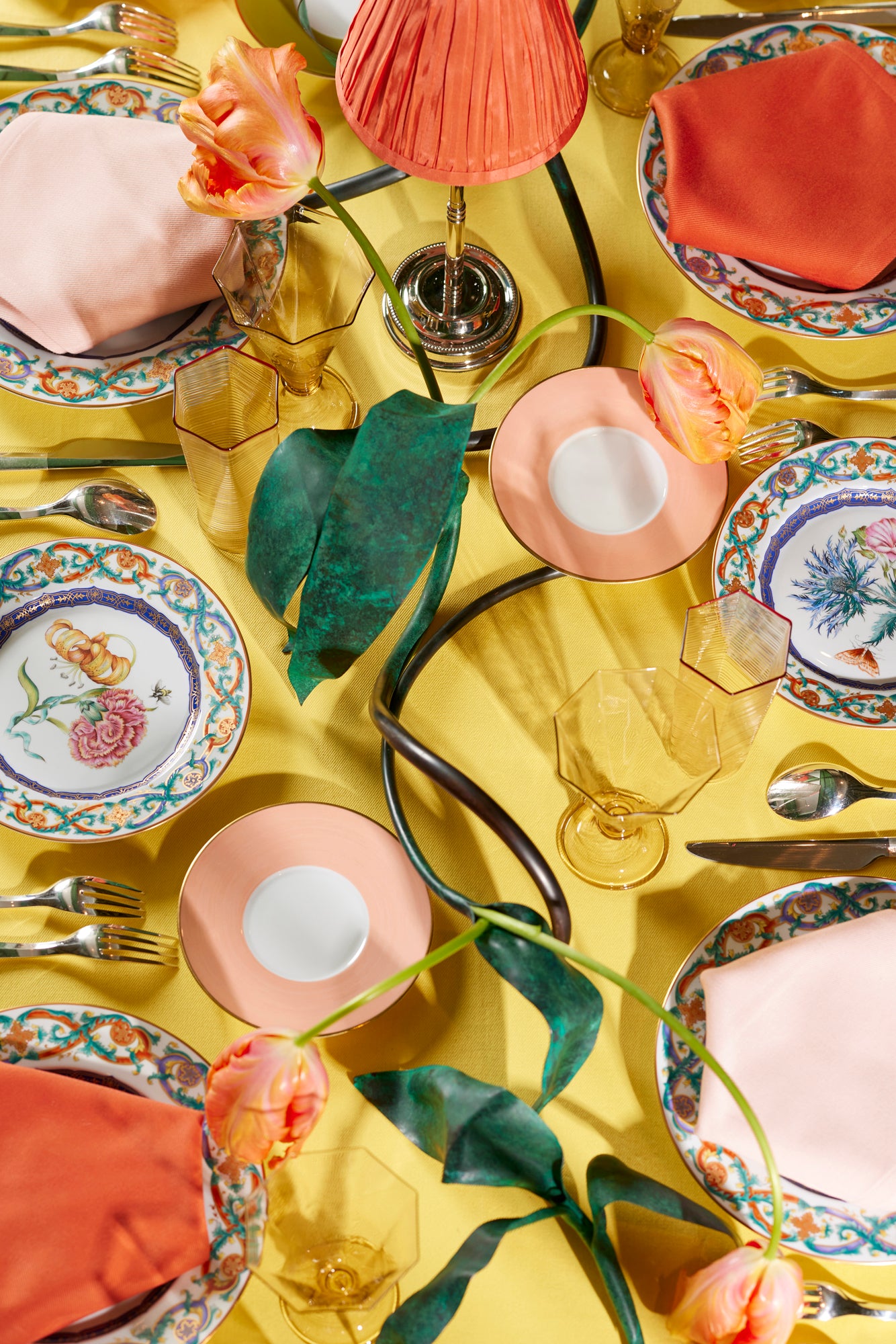 Spring tablescape with Herend Salmon Lexington plates, metal tulip vessel, coral lampshade, venetian glass goblets and colorblock lapkins and tablecloth.