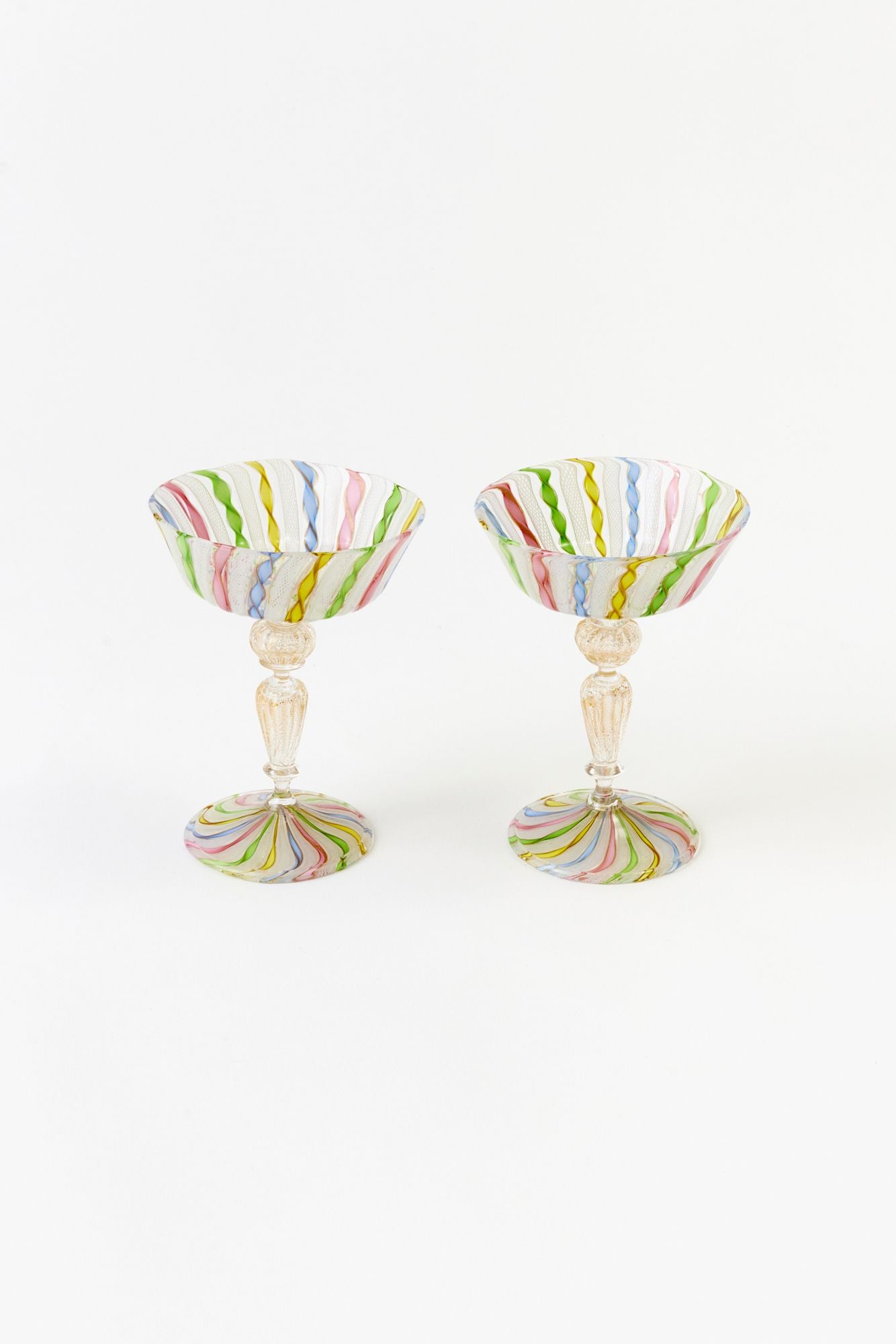 Two colorful striped cocktail glasses on a white background