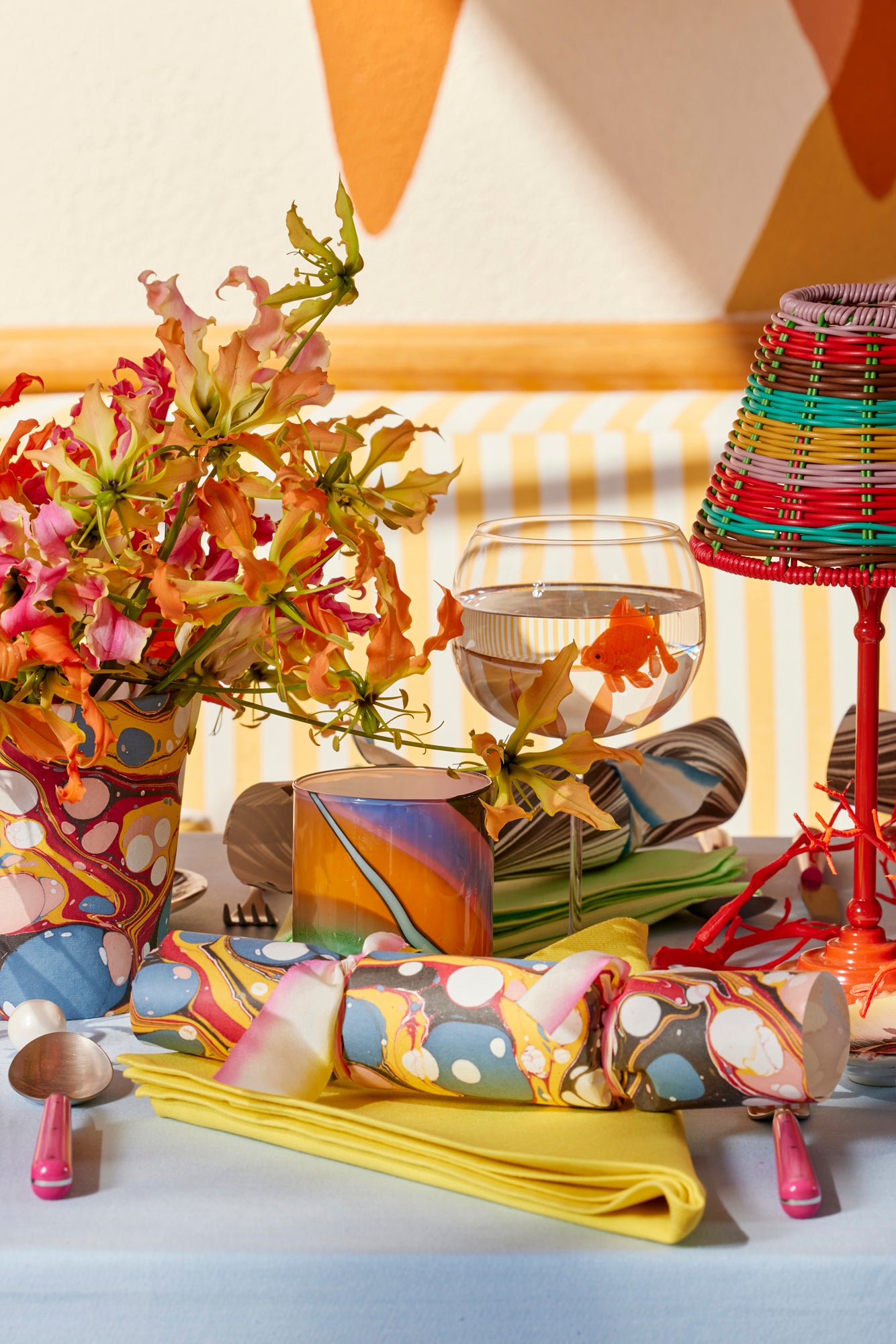 Under the Sea tablescape with marbled party crackers, color-block linens, woven lamp shade, and hot pink flatware.