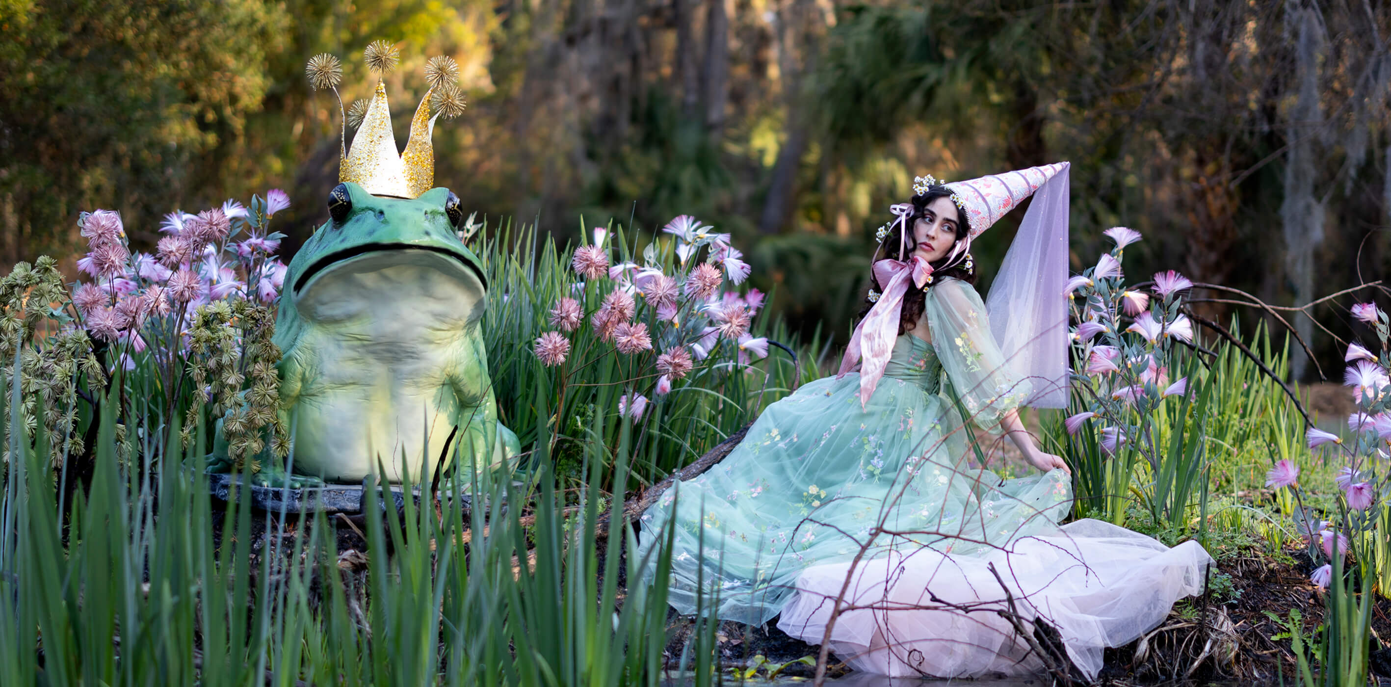 A princess and frog prince statue sit next to a pond