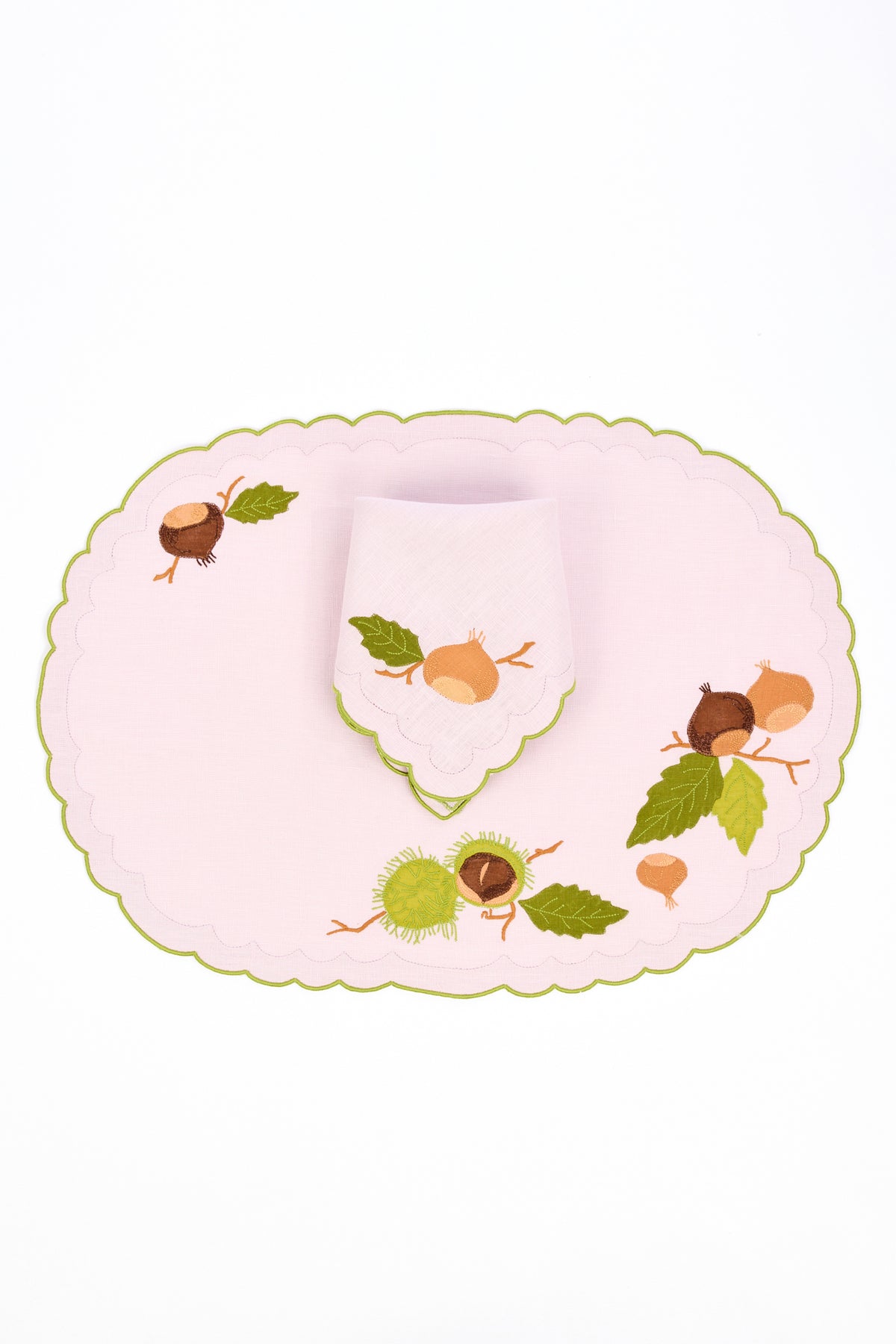 Pink scalloped linen placemat and dinner napkin with green stitched border. Hand stitched brown and green chestnut appliqués loosely patterned on top.
