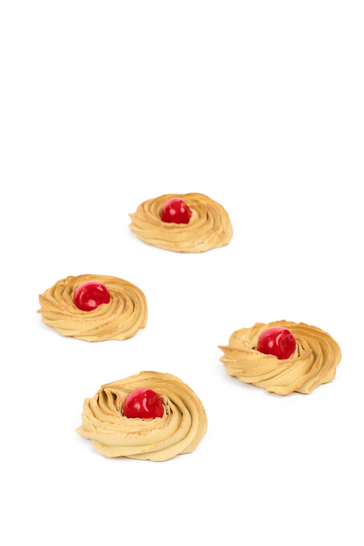 Faux Porcelain Italian swirled cookies with faux glossy red cherries against a clean white backdrop.