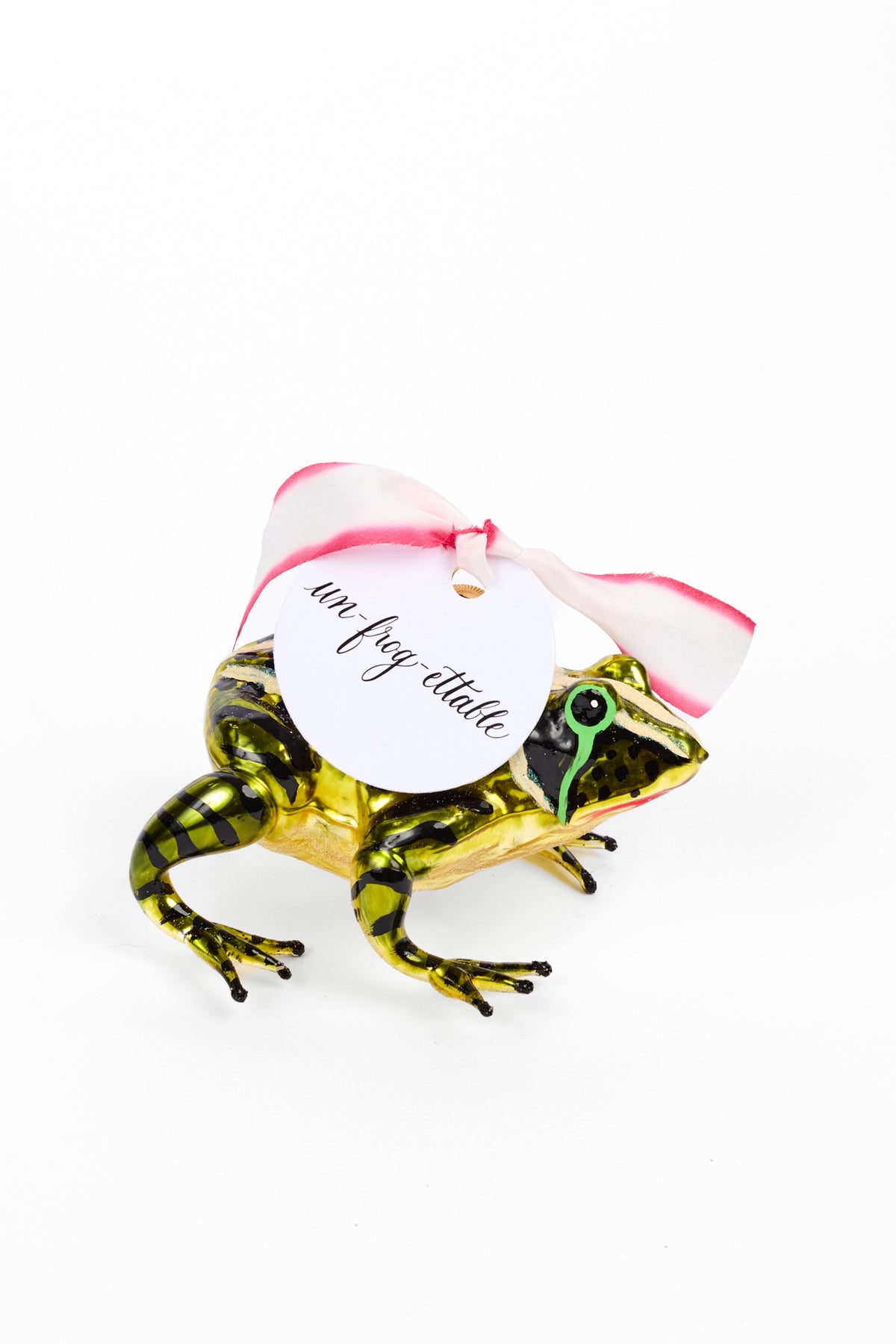 Ornament of a green frog with pink and white silk ribbon and a tag that says "un-frog-ettable"